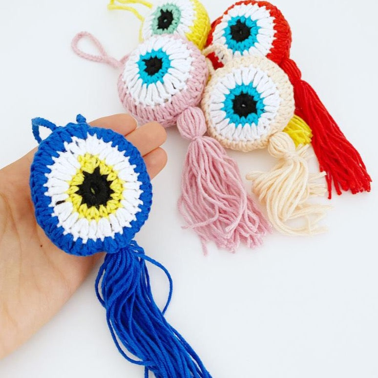 A beautifully crafted Handmade Evil Eye wall hanging featuring a vibrant blue eye symbol, intricately knitted, perfect for home decor or as a car charm.