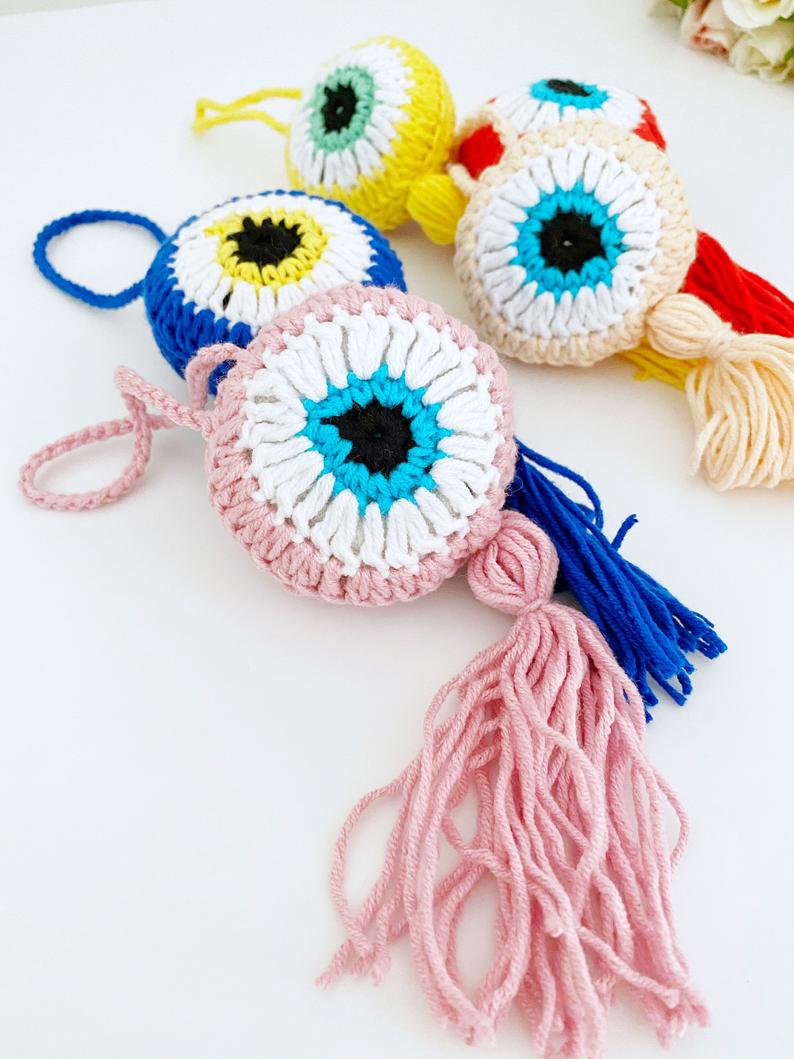 A beautifully crafted Handmade Evil Eye wall hanging featuring a vibrant blue eye symbol, intricately knitted, perfect for home decor or as a car charm.