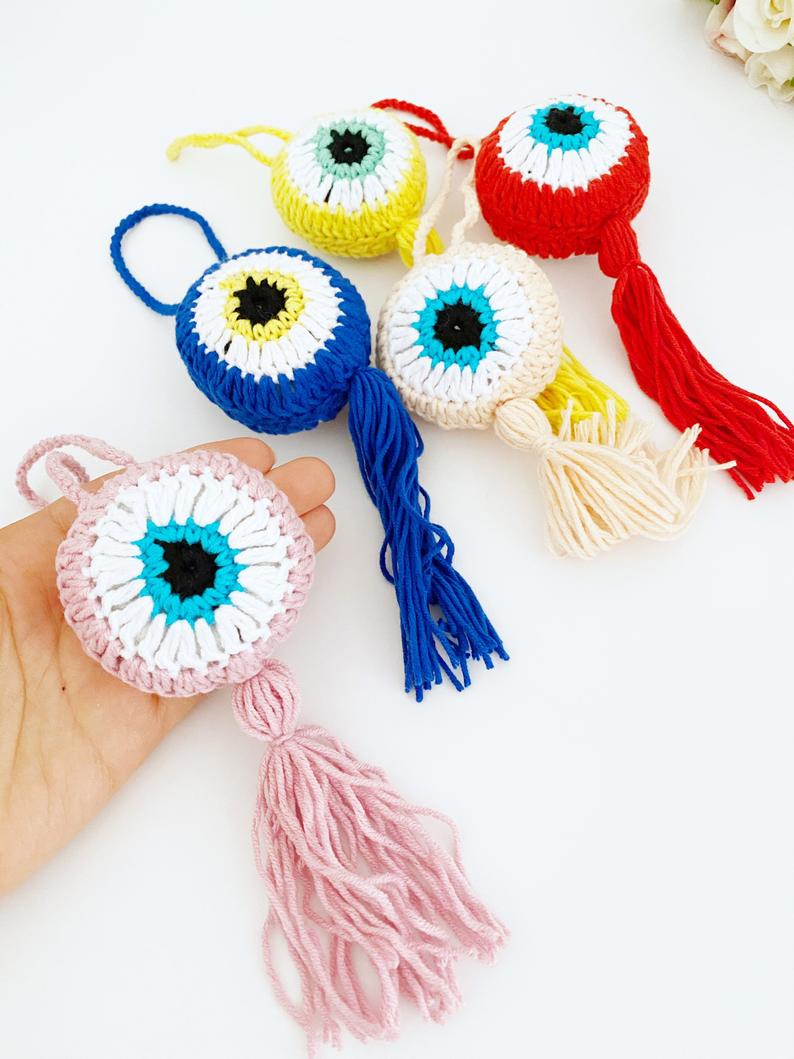 A beautifully crafted Handmade Evil Eye wall hanging featuring a vibrant blue eye symbol, intricately knitted, perfect for home decor or as a car charm.