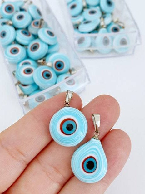 Handmade glass evil eye charm in turquoise, featuring round and oval shapes, perfect for jewelry making.