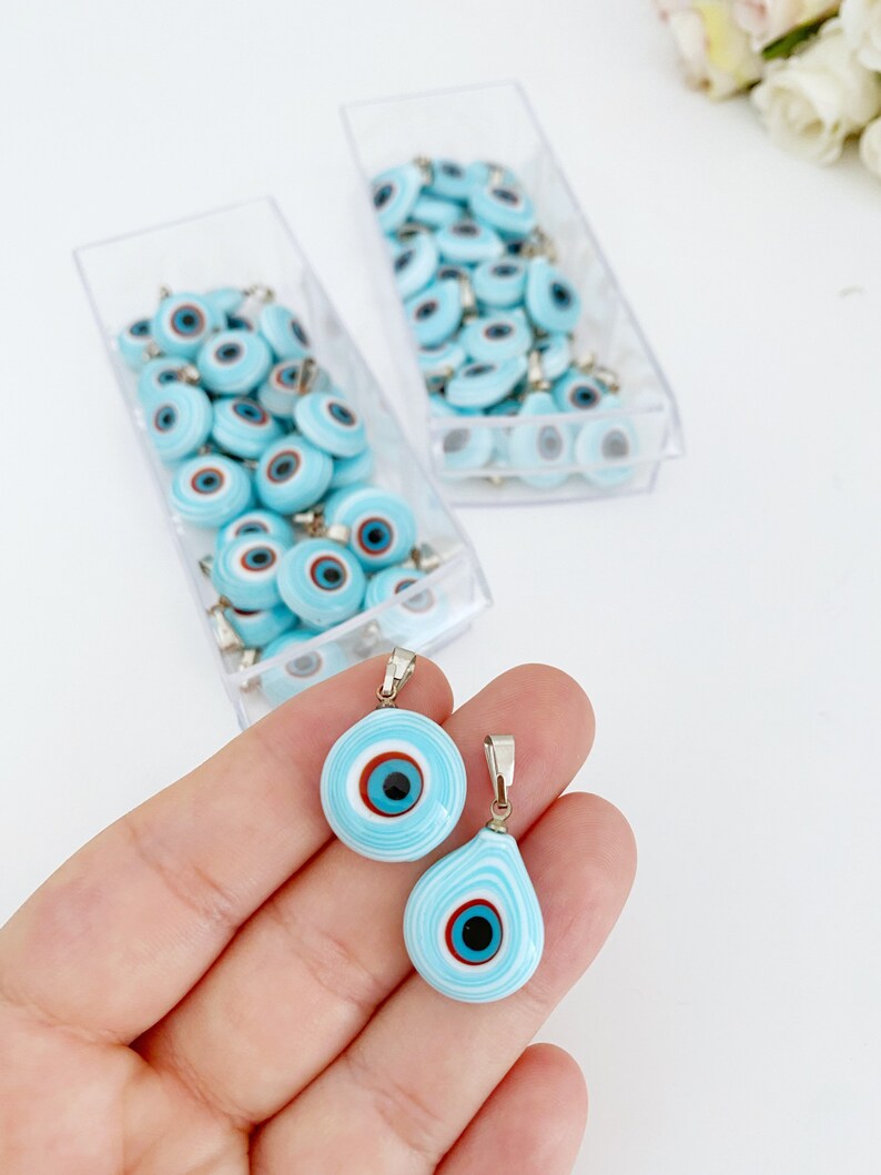 Handmade glass evil eye charm in turquoise, featuring round and oval shapes, perfect for jewelry making.