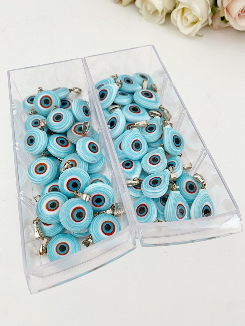 Handmade glass evil eye charm in turquoise, featuring round and oval shapes, perfect for jewelry making.