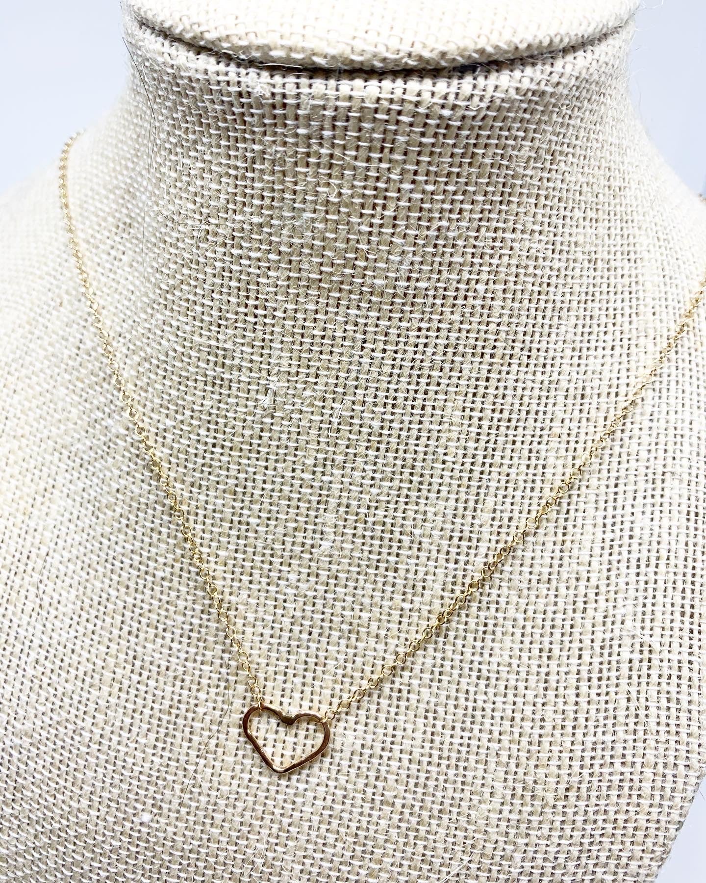 A delicate heart charm necklace featuring a rustic hammered heart pendant on an adjustable cable chain, symbolizing love and joy.