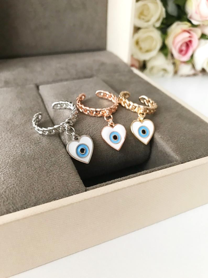 Heart Evil Eye Dangle Ring featuring white evil eye beads and adjustable design in silver, gold, and rose gold finishes.