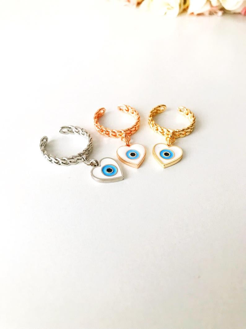 Heart Evil Eye Dangle Ring featuring white evil eye beads and adjustable design in silver, gold, and rose gold finishes.