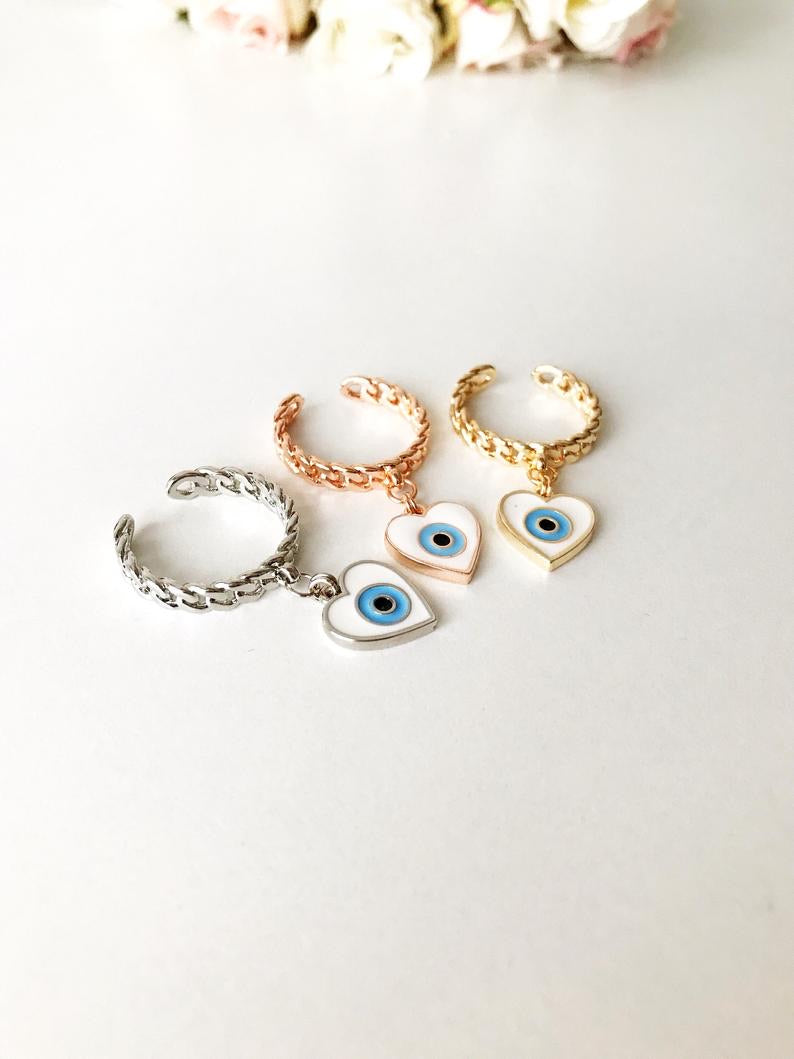 Heart Evil Eye Dangle Ring featuring white evil eye beads and adjustable design in silver, gold, and rose gold finishes.