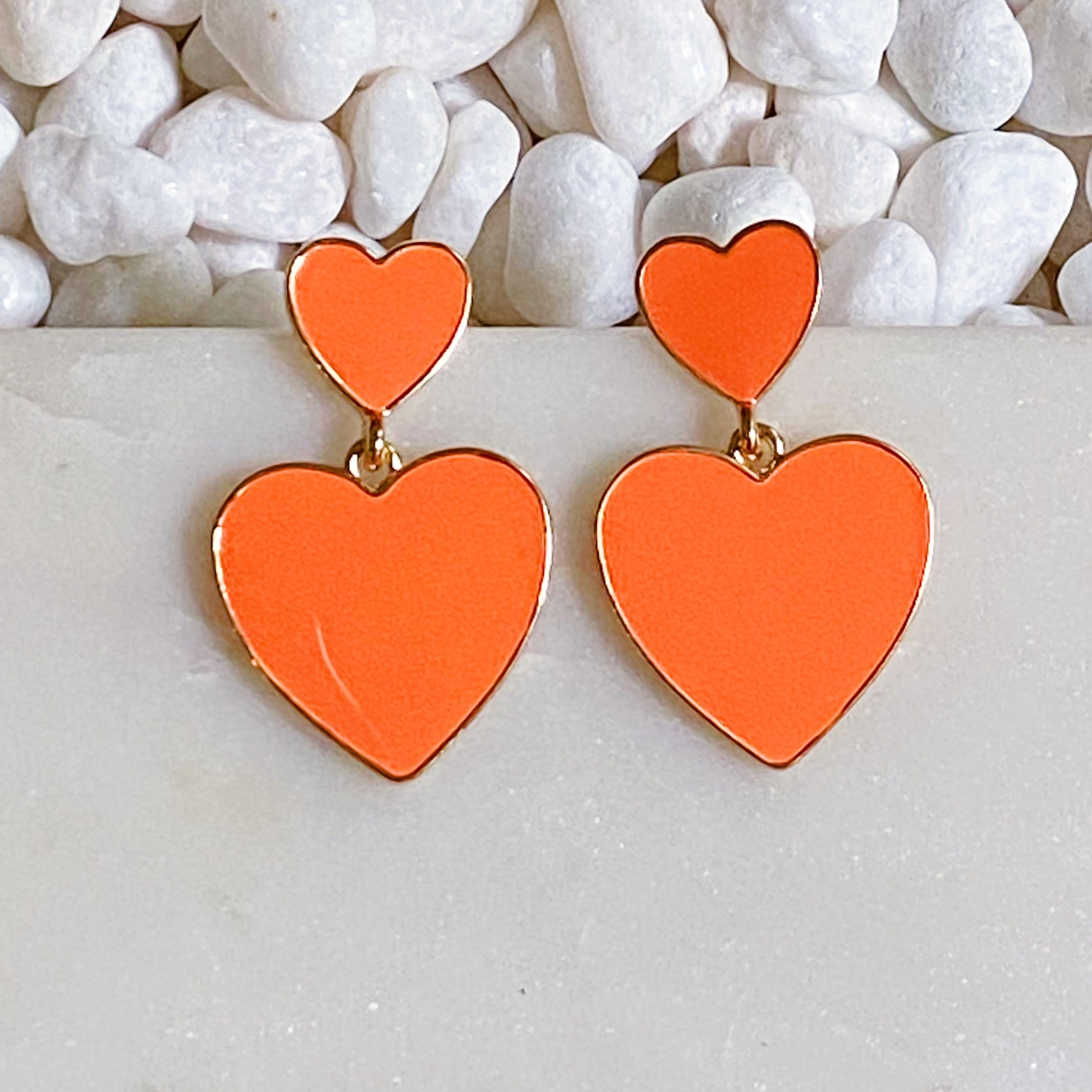 Trendy double heart earrings with glossy enamel finish in gold tone, perfect for game day or casual wear.