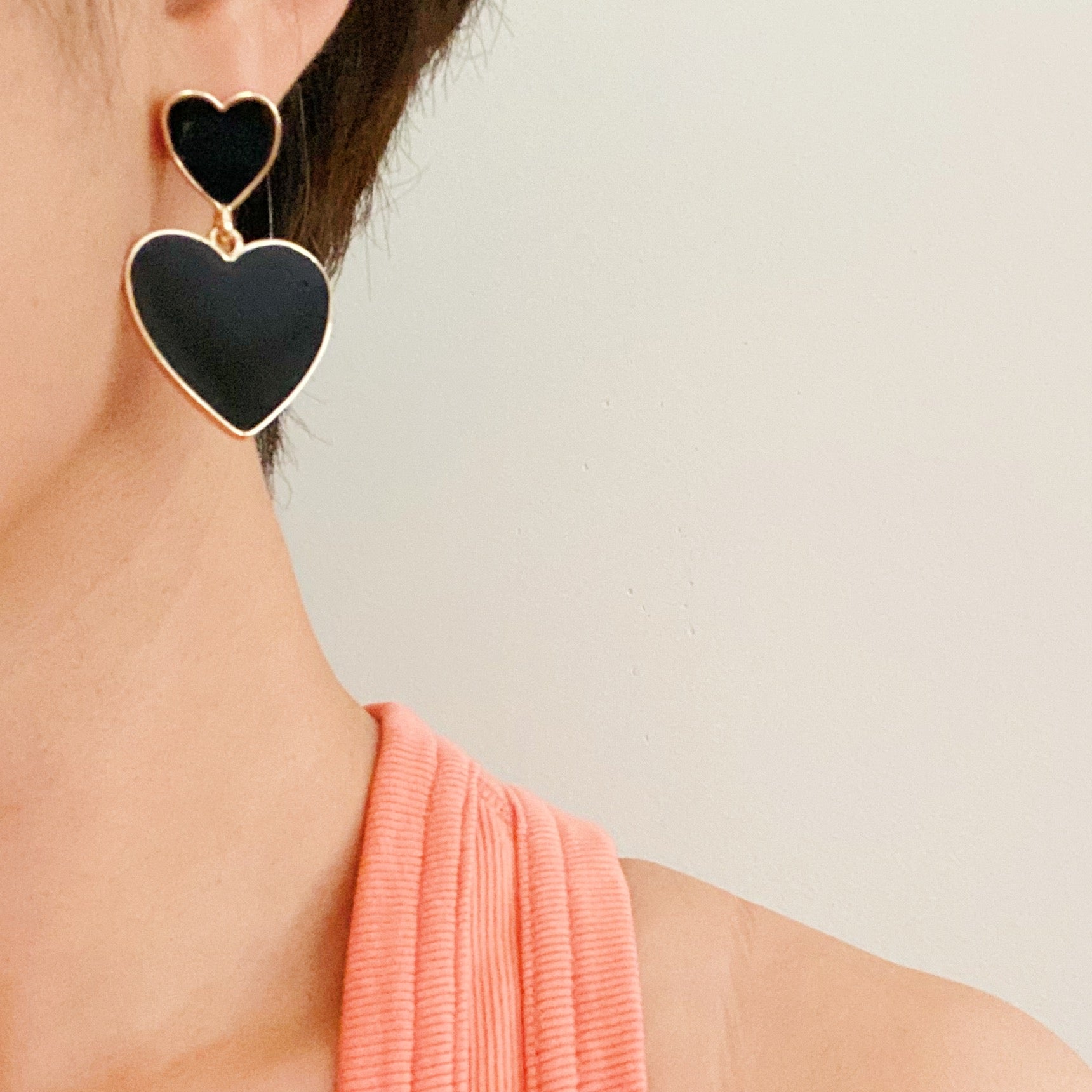 Trendy double heart earrings with glossy enamel finish in gold tone, perfect for game day or casual wear.