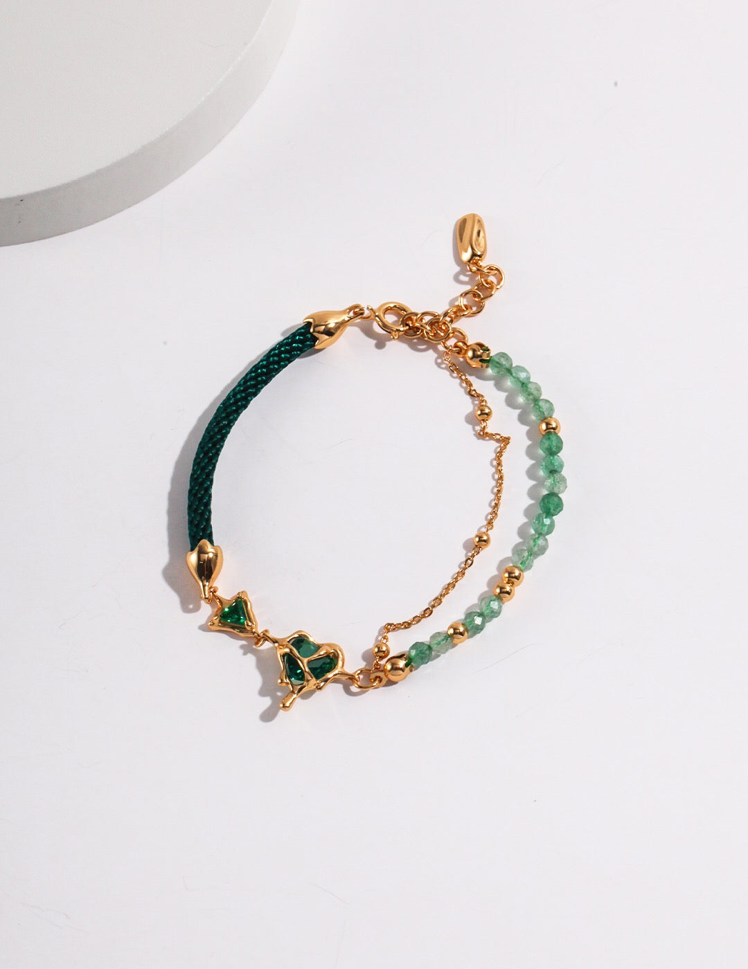 A handmade Heart Green Strawberry Crystal Bracelet featuring zircon stones and gold vermeil, elegantly displayed on a soft surface.