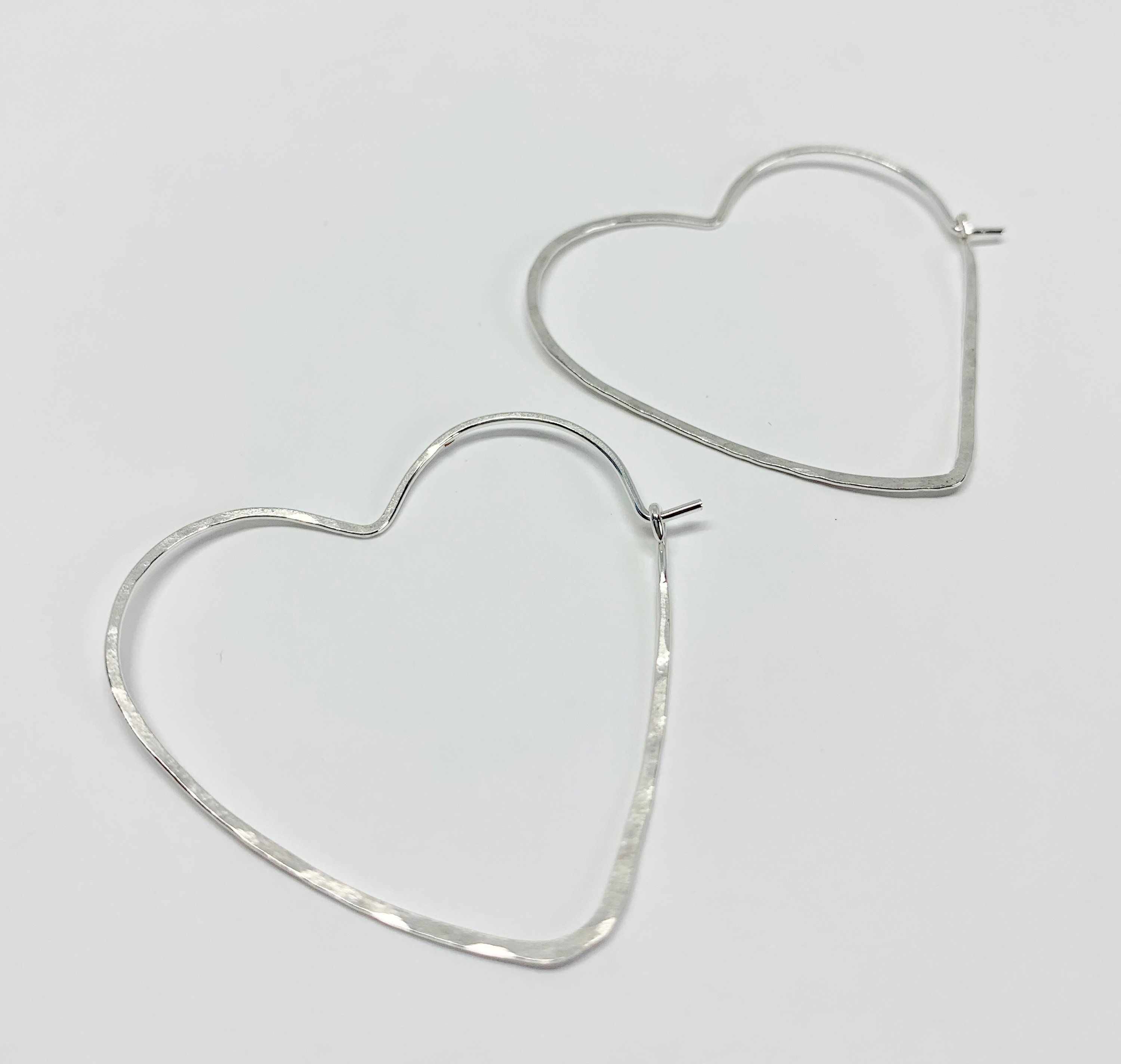 Large heart-shaped hoops made from 20 gauge wire, featuring a hammered texture for shine, available in silver, yellow gold fill, and rose gold fill.