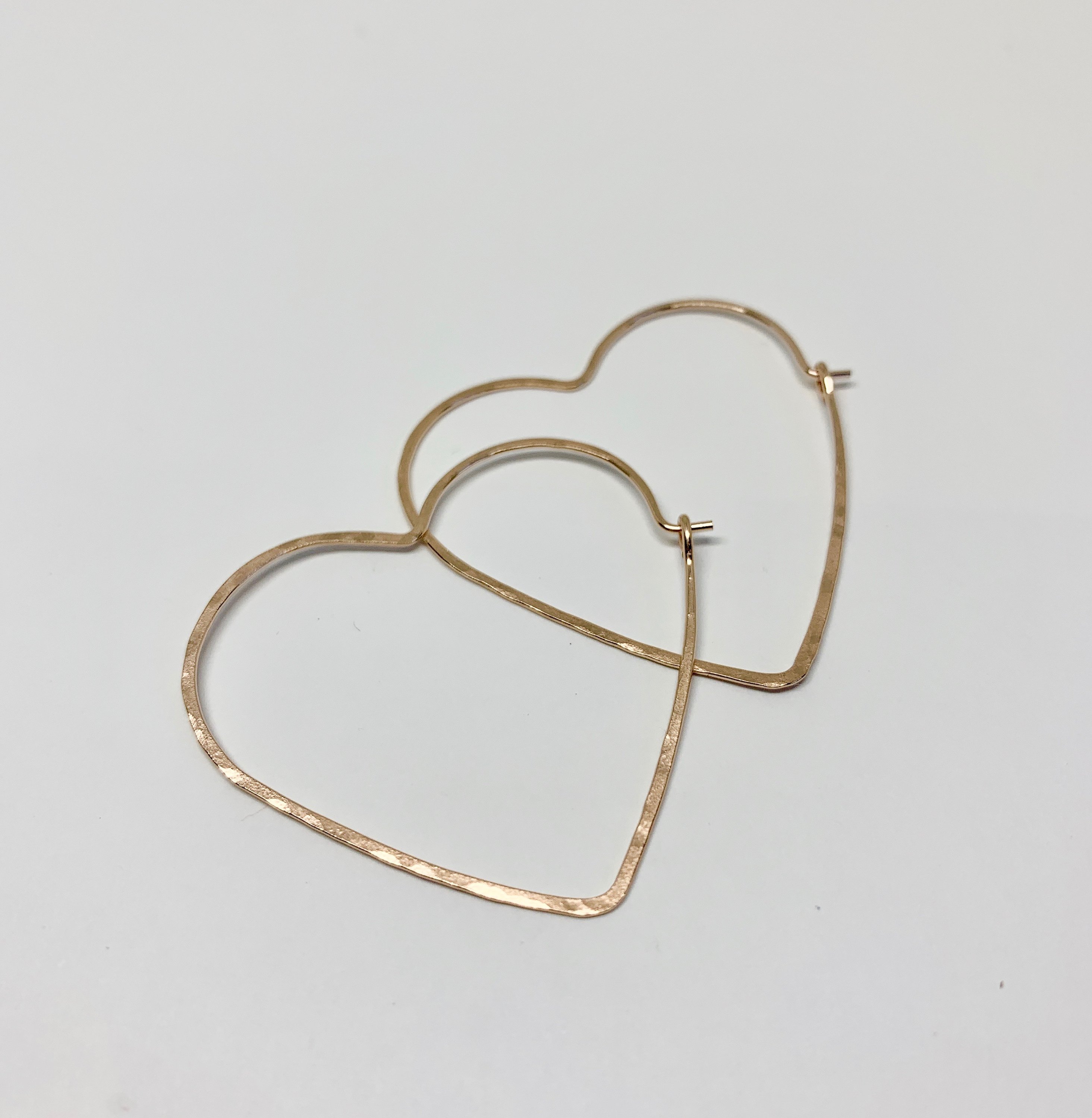 Large heart-shaped hoops made from 20 gauge wire, featuring a hammered texture for shine, available in silver, yellow gold fill, and rose gold fill.