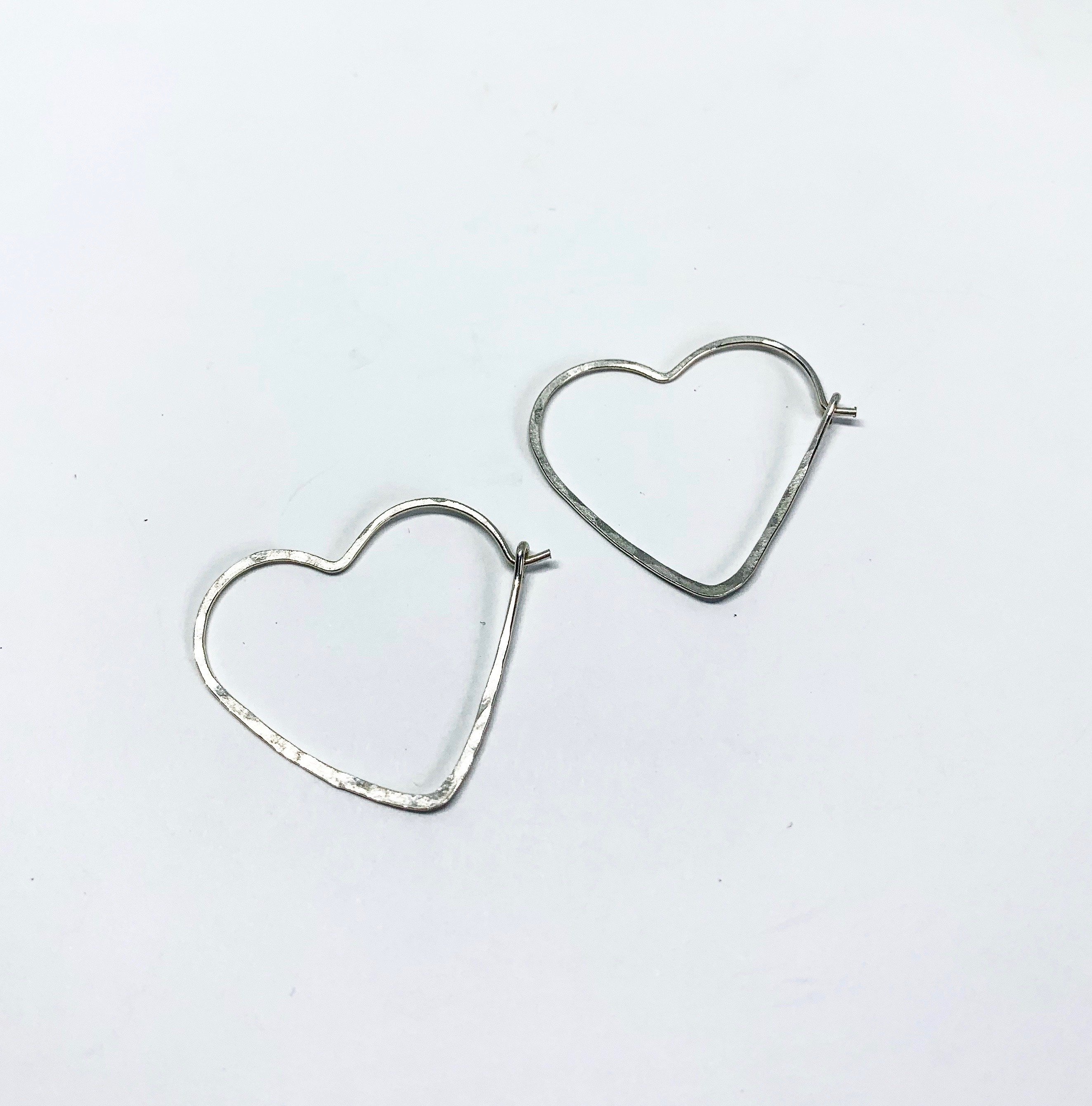 A pair of small heart-shaped hoop earrings made from 20 gauge wire, featuring a hammered texture for added shine, available in silver, yellow gold fill, and rose gold fill.