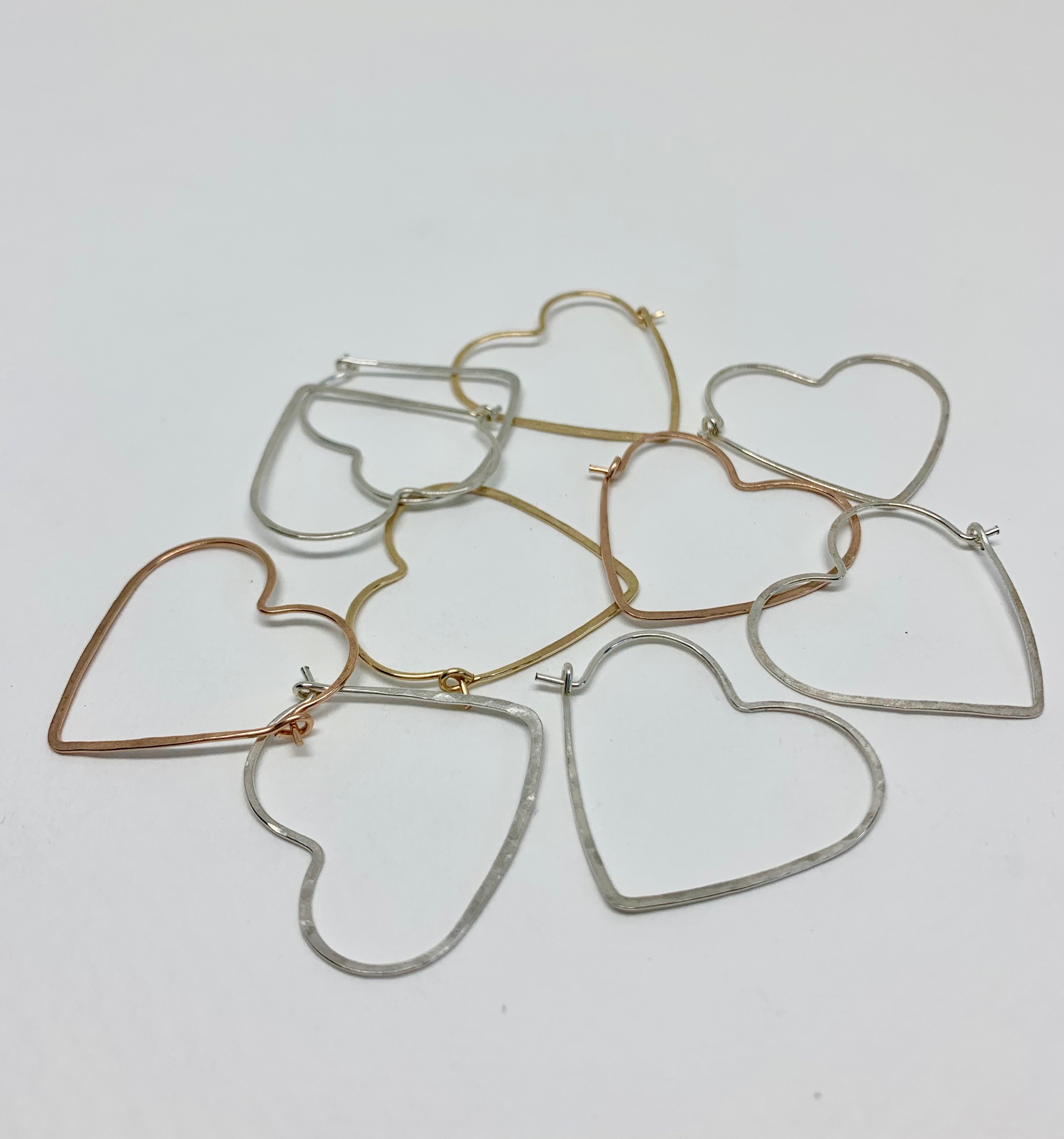 A pair of small heart-shaped hoop earrings made from 20 gauge wire, featuring a hammered texture for added shine, available in silver, yellow gold fill, and rose gold fill.