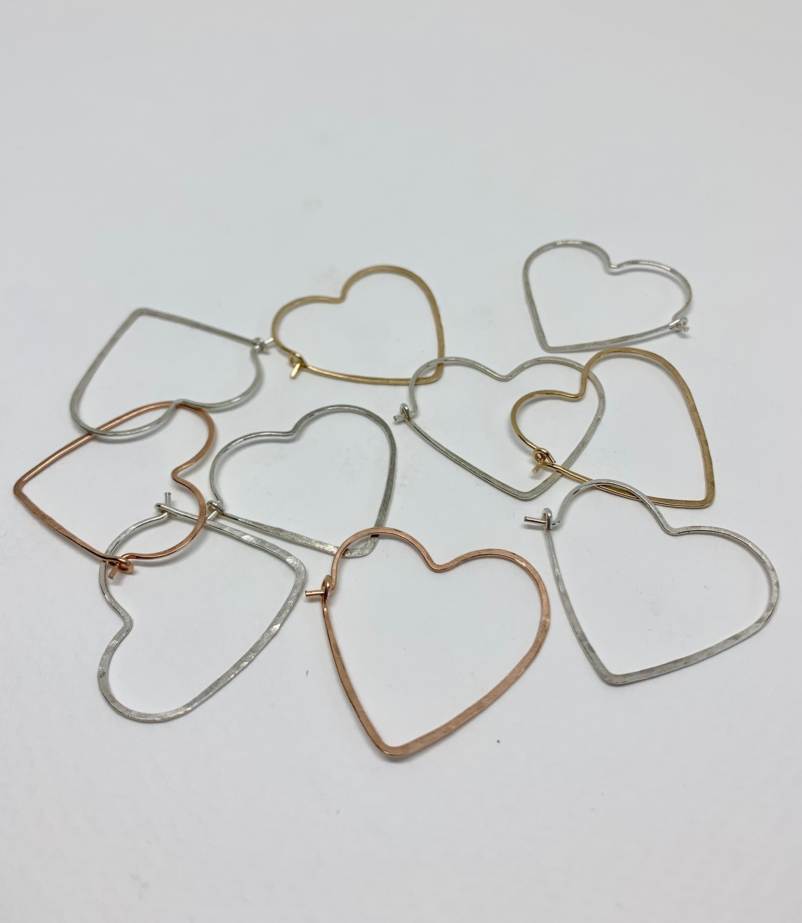 A pair of small heart-shaped hoop earrings made from 20 gauge wire, featuring a hammered texture for added shine, available in silver, yellow gold fill, and rose gold fill.