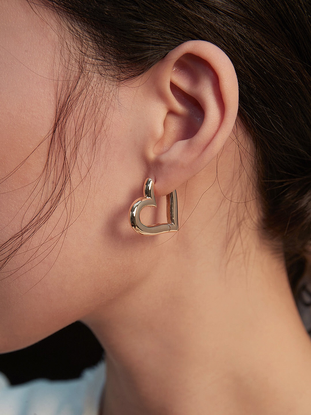 A pair of elegant heart shape hoop earrings made from sterling silver with a gold vermeil finish, showcasing their unique design and craftsmanship.