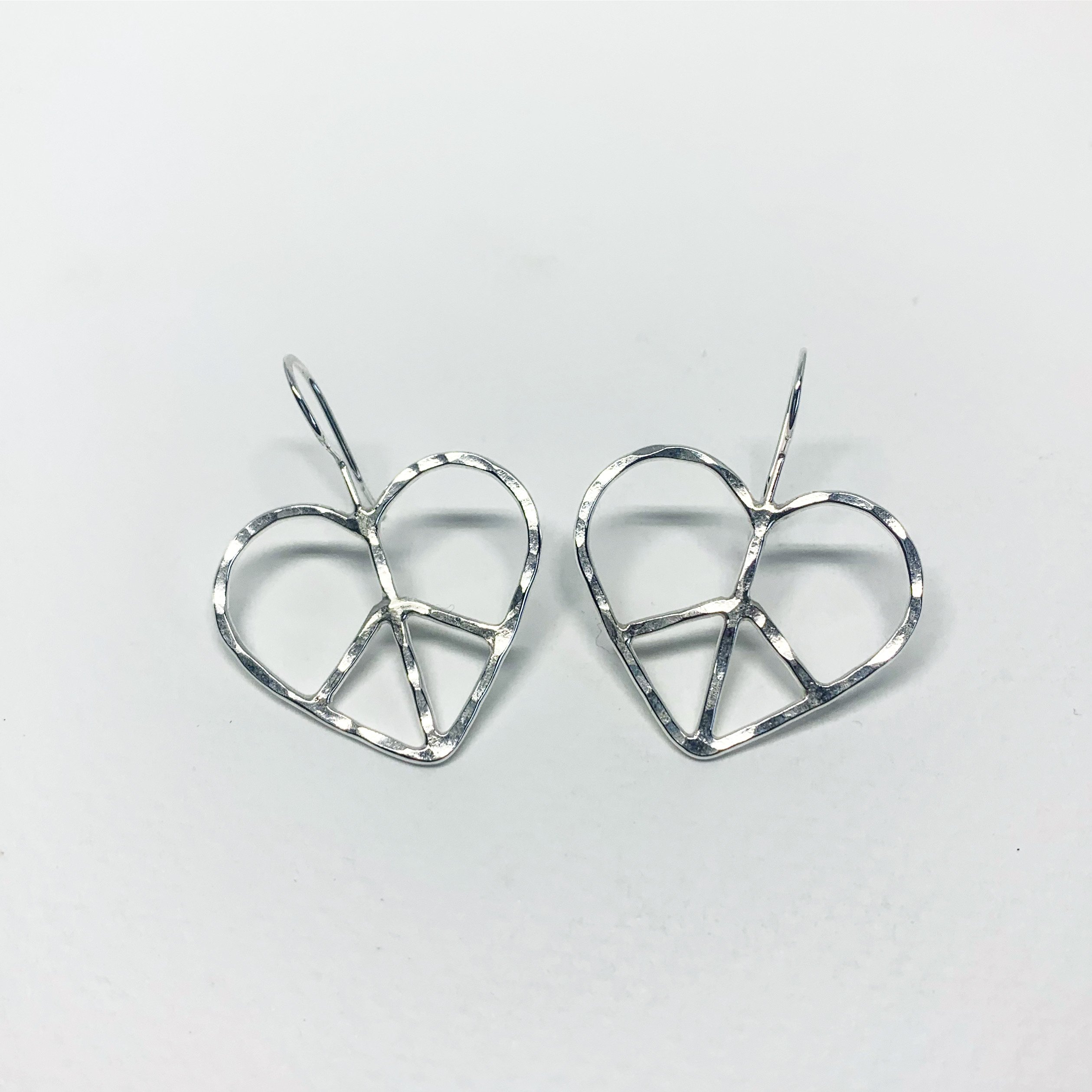 Handmade heart shaped peace sign earrings with a rustic hammered texture, crafted from recycled metals in Hermosa Beach, California.