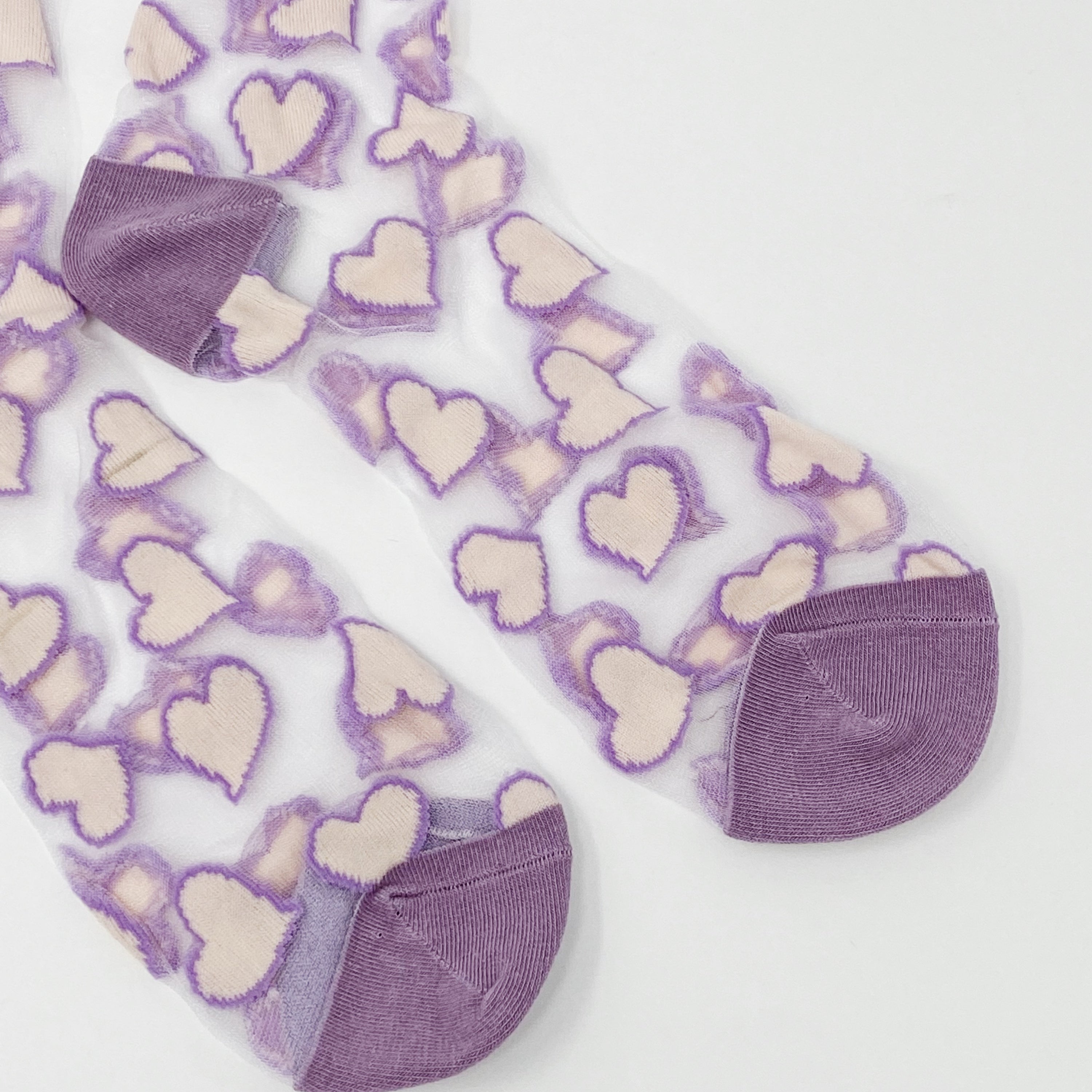 A pair of sheer socks featuring a playful heart pattern, showcasing their soft texture and stylish design.