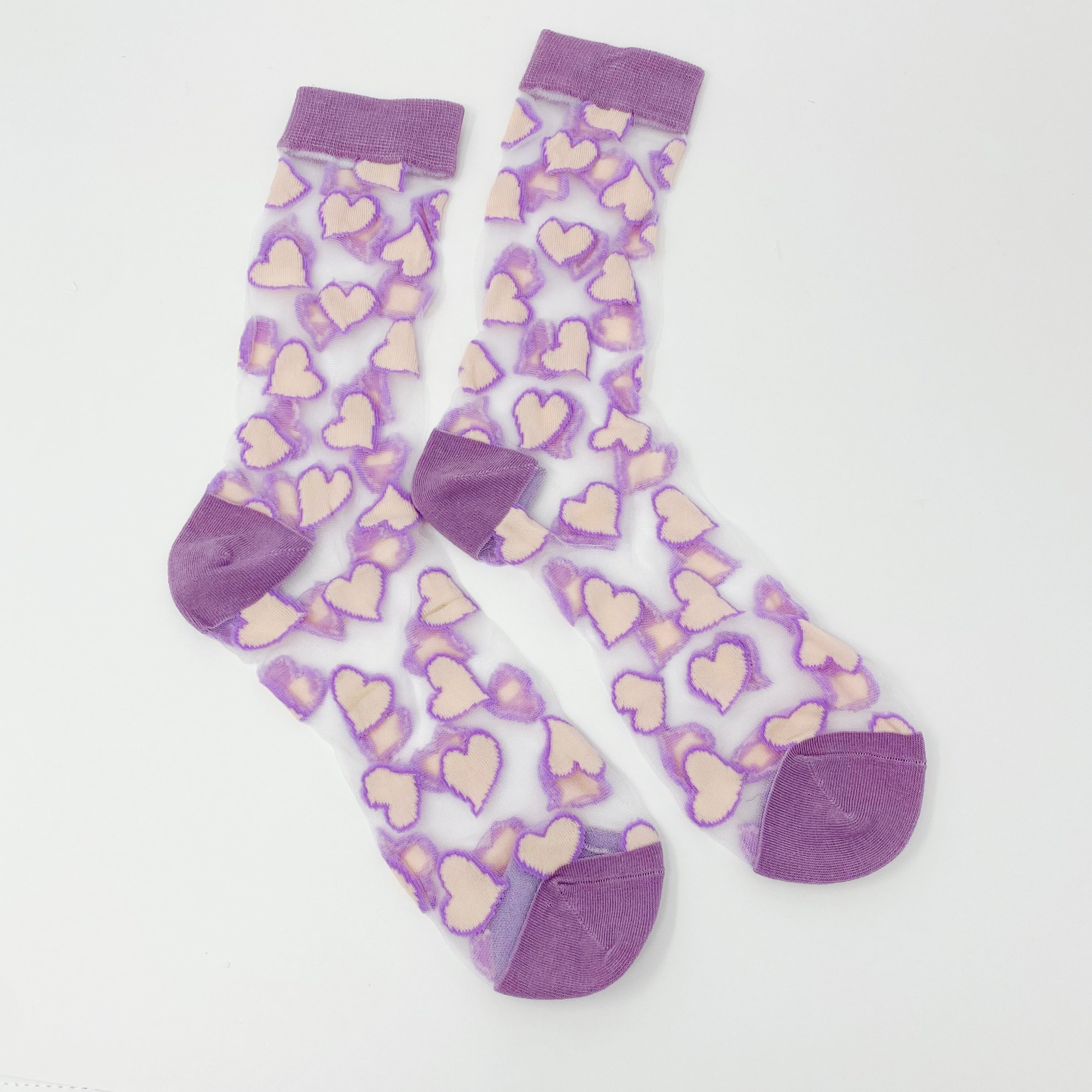 A pair of sheer socks featuring a playful heart pattern, showcasing their soft texture and stylish design.