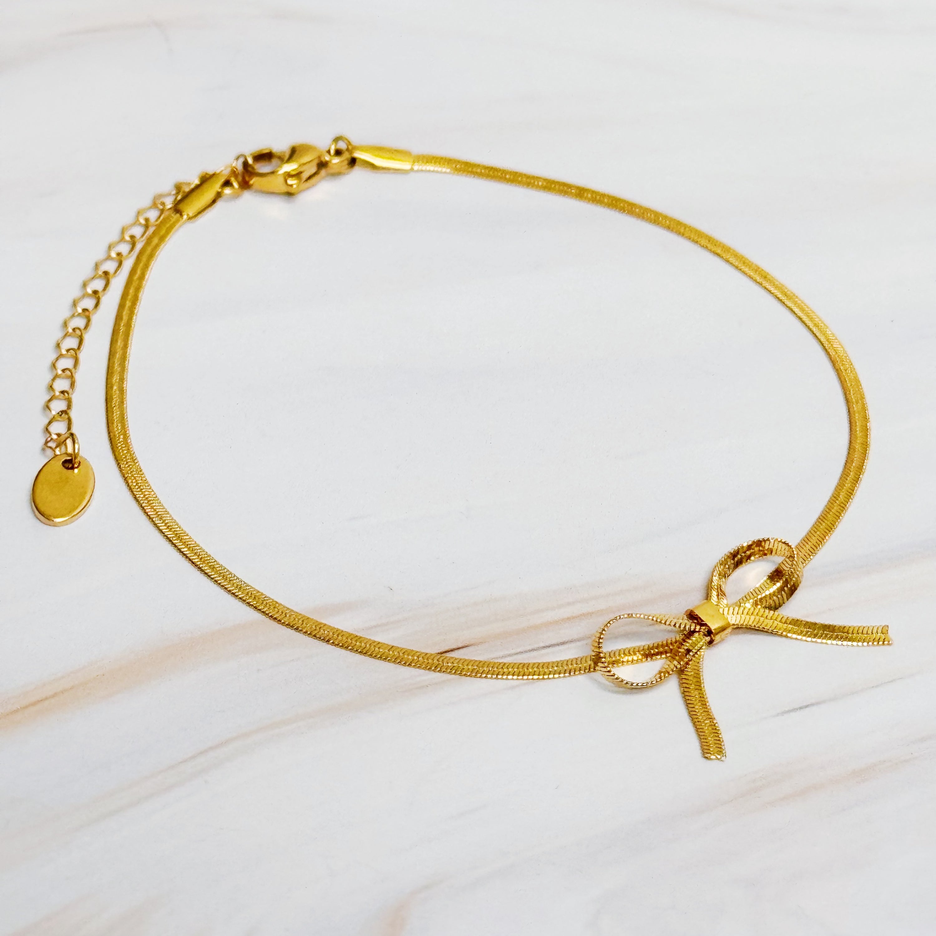 Elegant Herringbone Chain Bow Anklet in 18k gold plated brass with a delicate bow design.