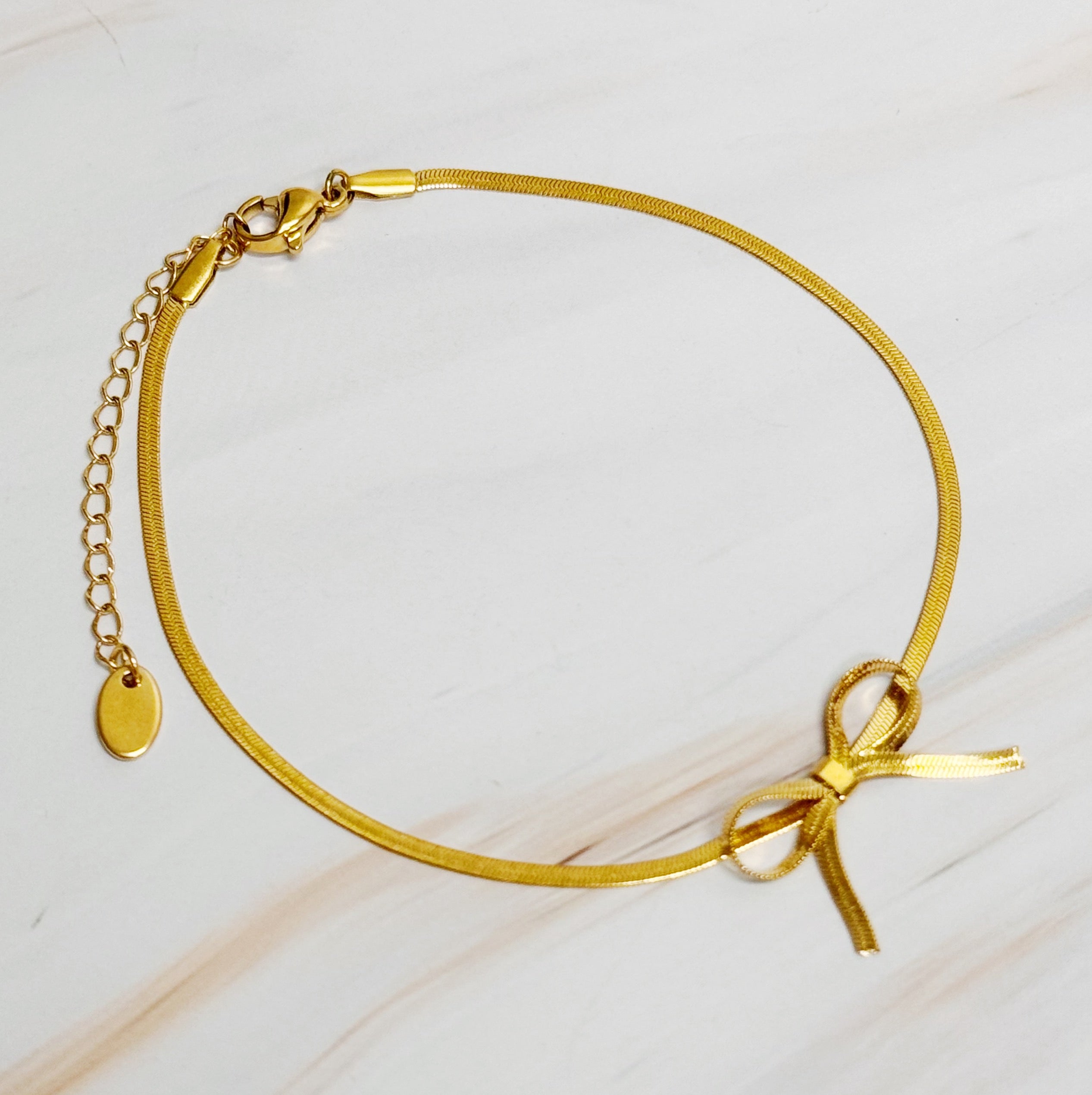 Elegant Herringbone Chain Bow Anklet in 18k gold plated brass with a delicate bow design.