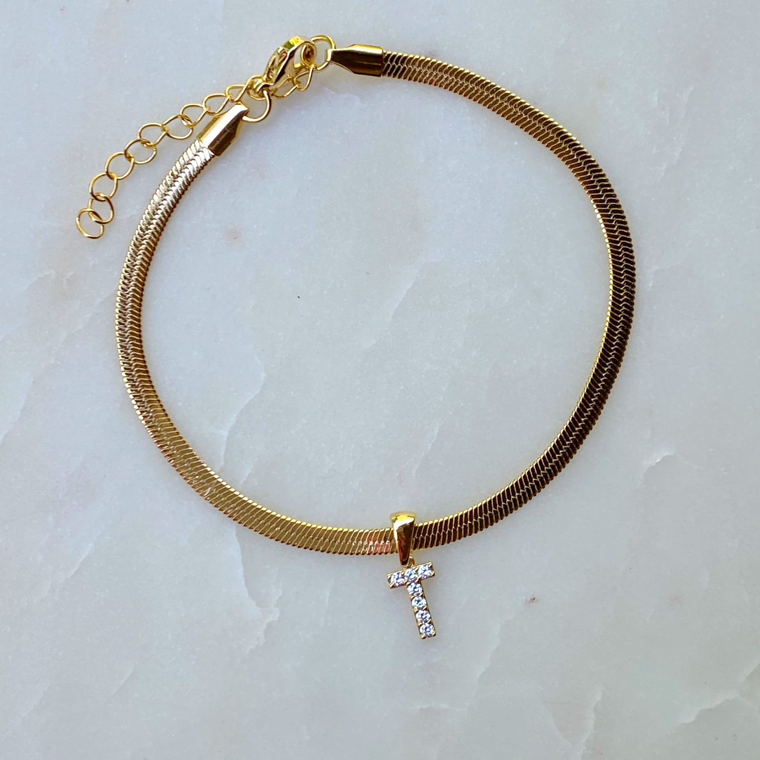 Elegant Herringbone Chain Initial Anklet with shiny initial charm, showcasing its gold plating and adjustable length.