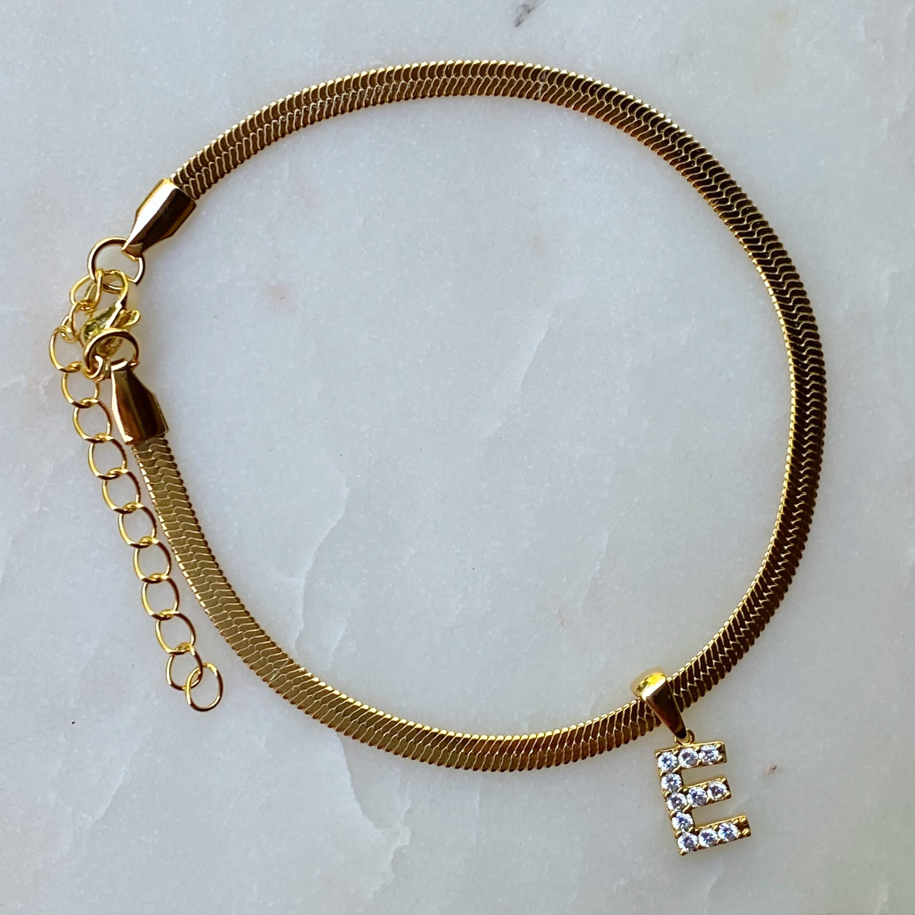 Elegant Herringbone Chain Initial Anklet with shiny initial charm, showcasing its gold plating and adjustable length.