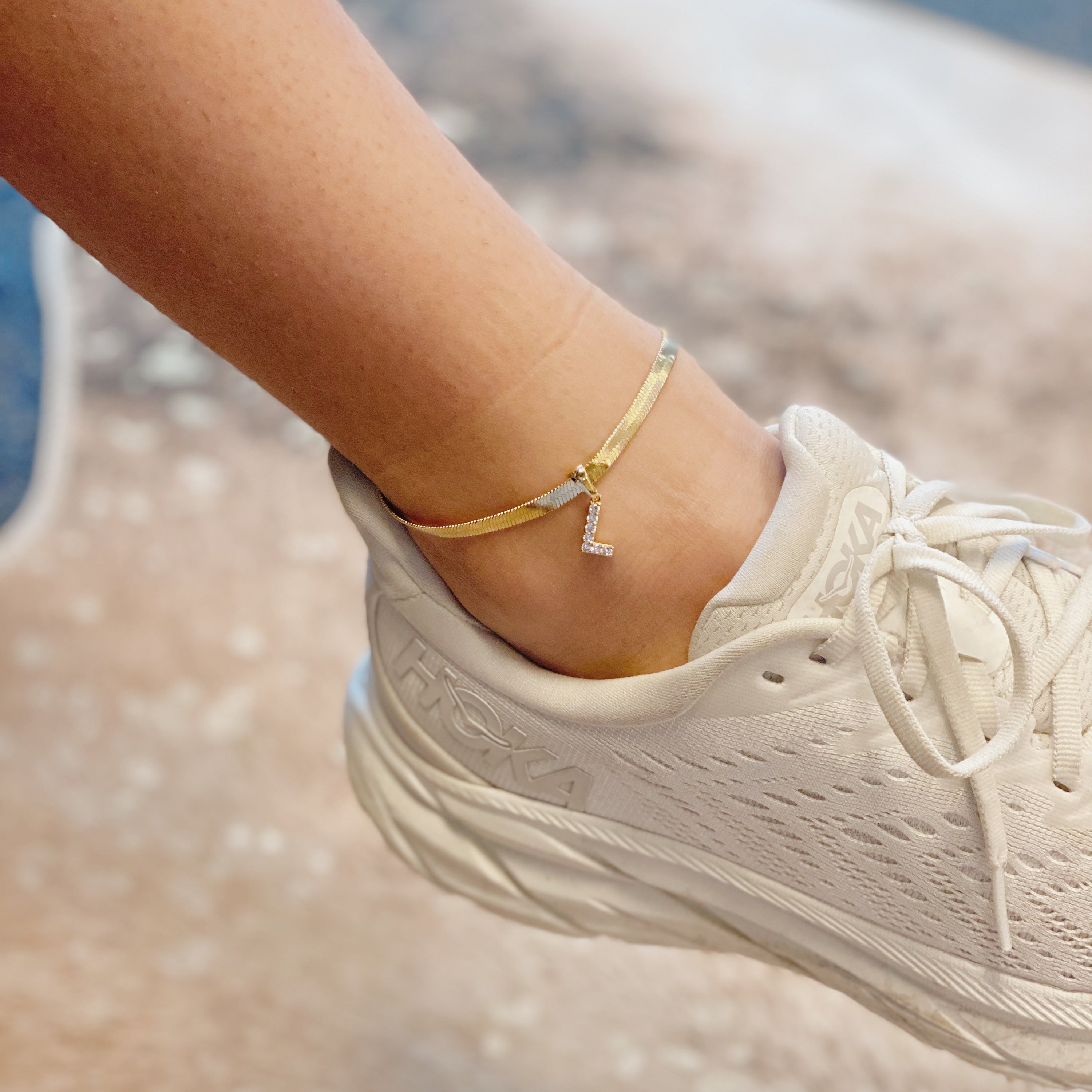 Elegant Herringbone Chain Initial Anklet with shiny initial charm, showcasing its gold plating and adjustable length.