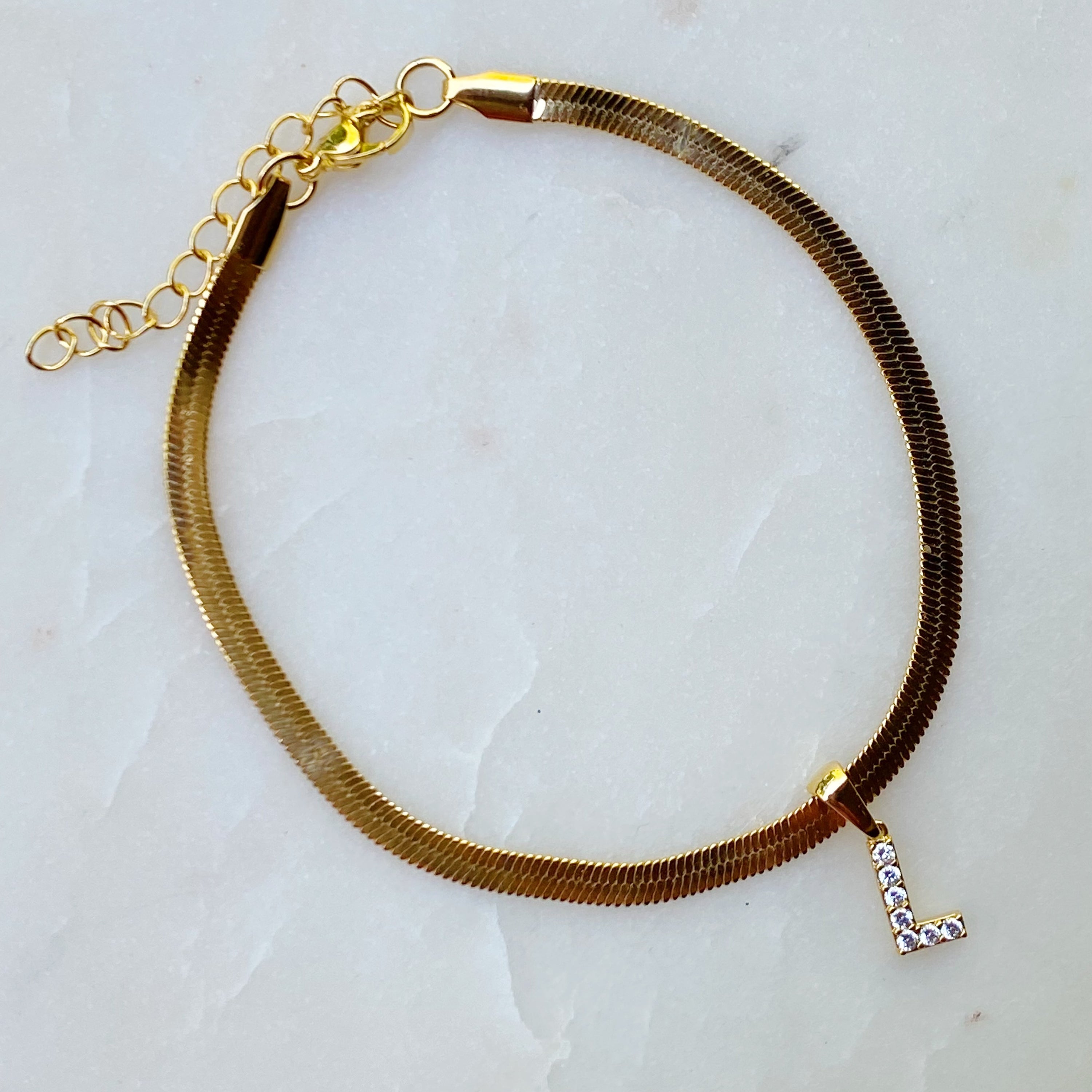 Elegant Herringbone Chain Initial Anklet with shiny initial charm, showcasing its gold plating and adjustable length.