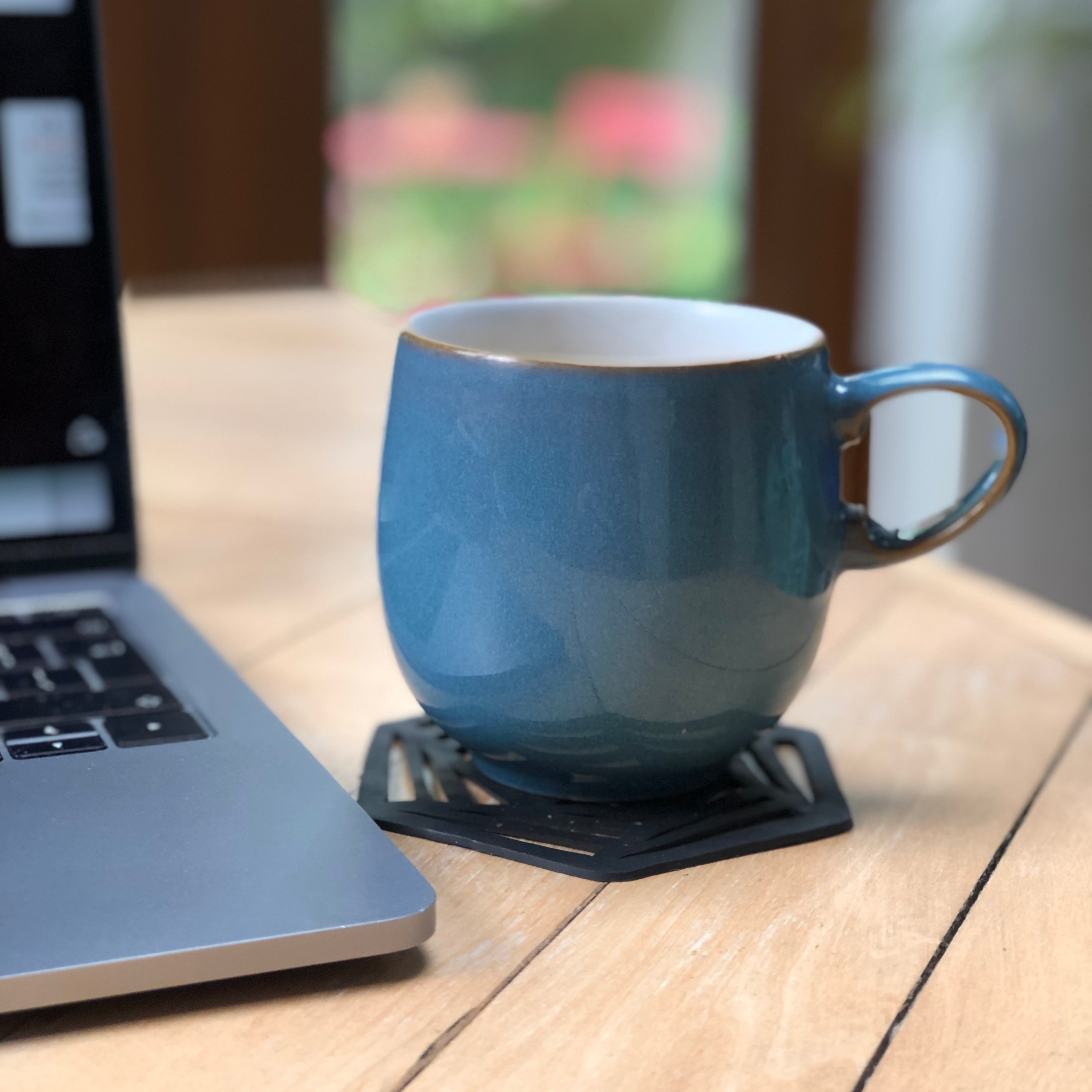 A set of two hexagon-shaped coasters made from recycled rubber, showcasing unique designs and textures.