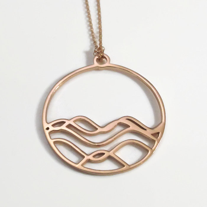 High Tide Ocean Wave Pendant in sterling silver, featuring a circular design inspired by ocean waves, displayed with a matching cable chain necklace.