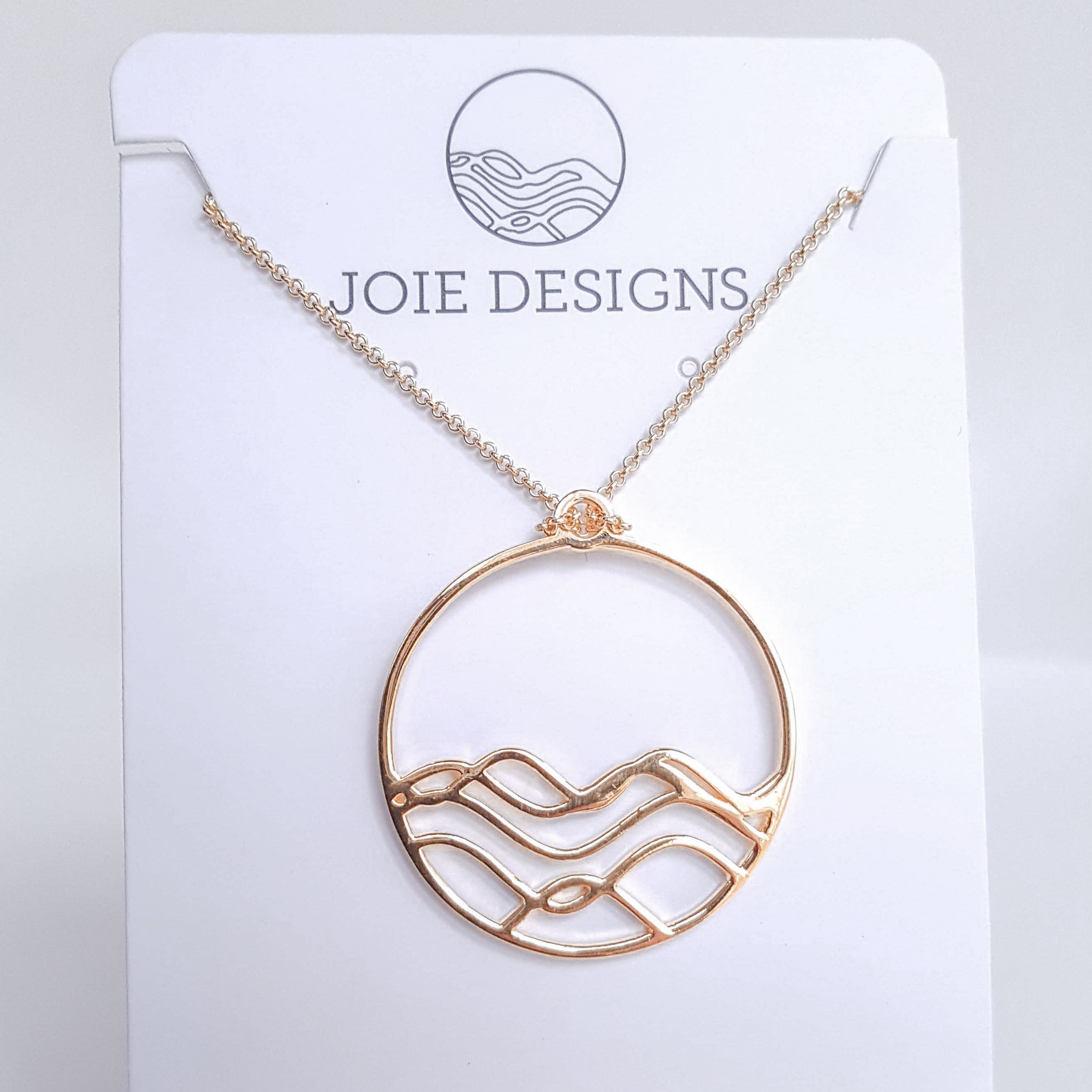 High Tide Ocean Wave Pendant in sterling silver, featuring a circular design inspired by ocean waves, displayed with a matching cable chain necklace.