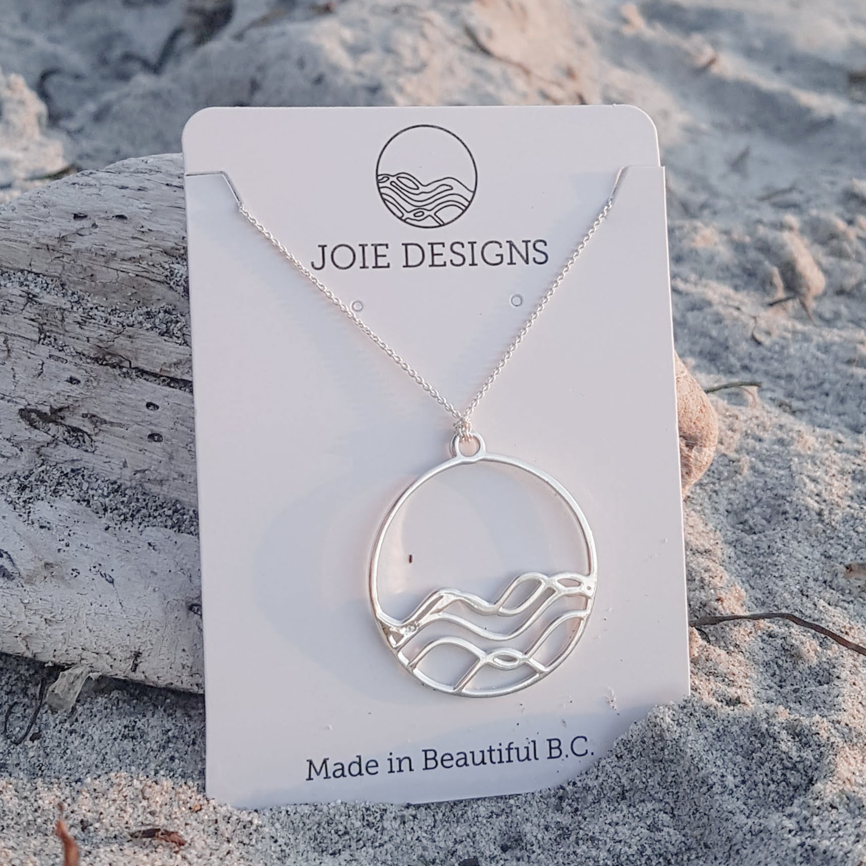 High Tide Ocean Wave Pendant in sterling silver, featuring a circular design inspired by ocean waves, displayed with a matching cable chain necklace.