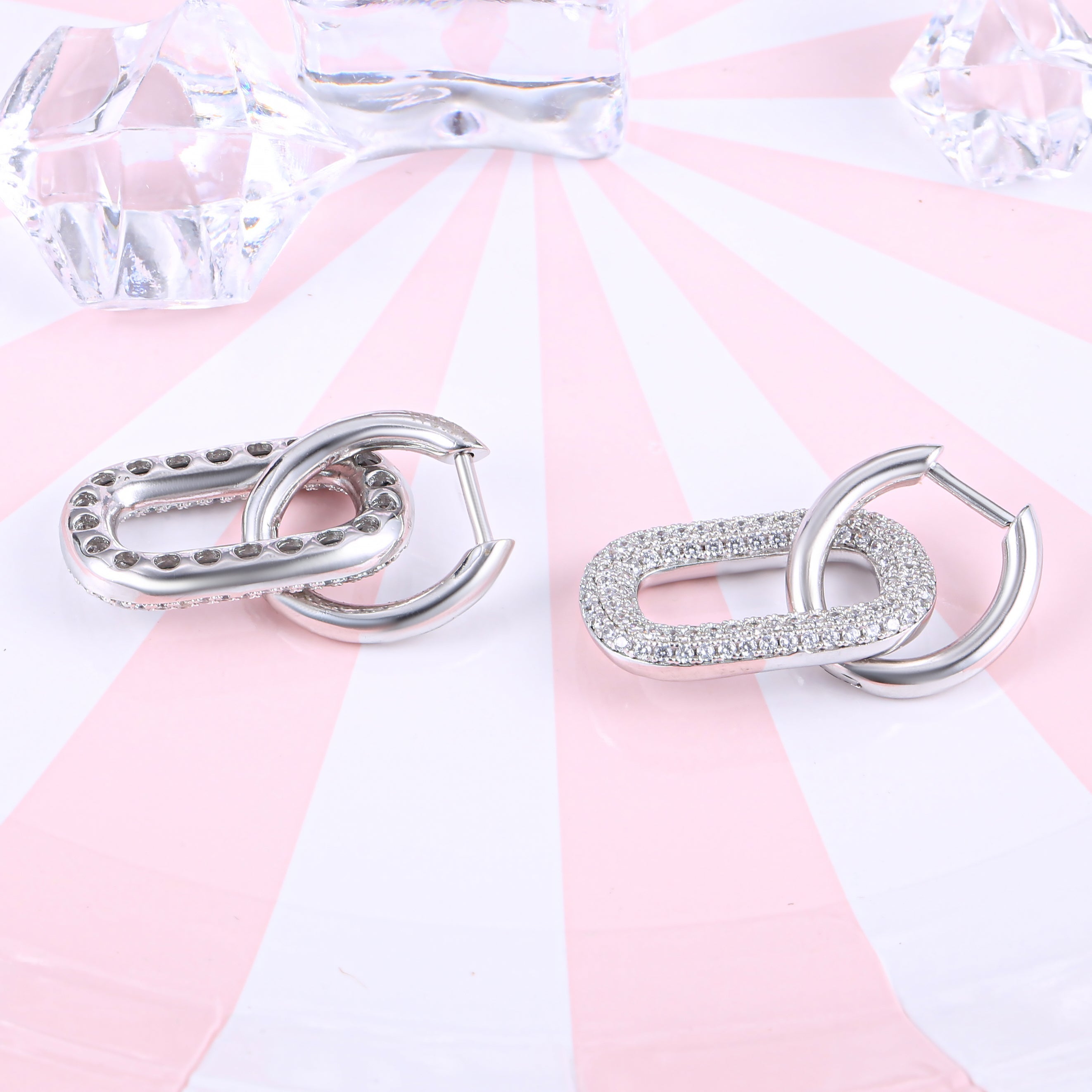 Hip hop Cuban chain link huggie hoop earrings made of 925 sterling silver with a white gold finish and adorned with white sapphire stones.