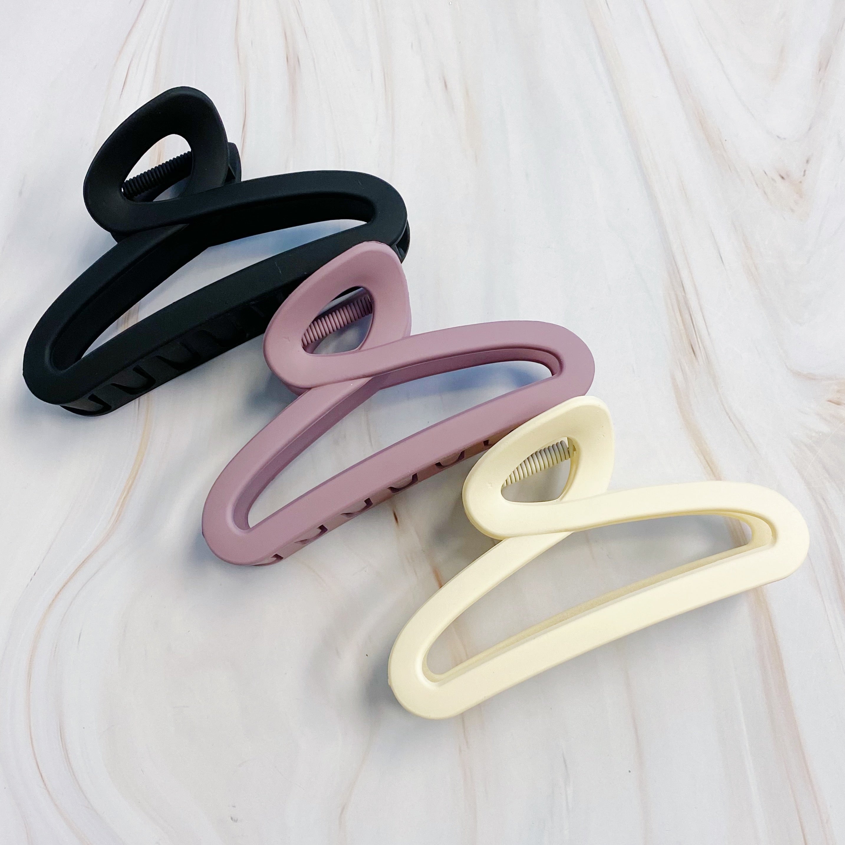 A stylish set of three hair claws in soft matte finish, showcasing various colors suitable for any hairstyle.