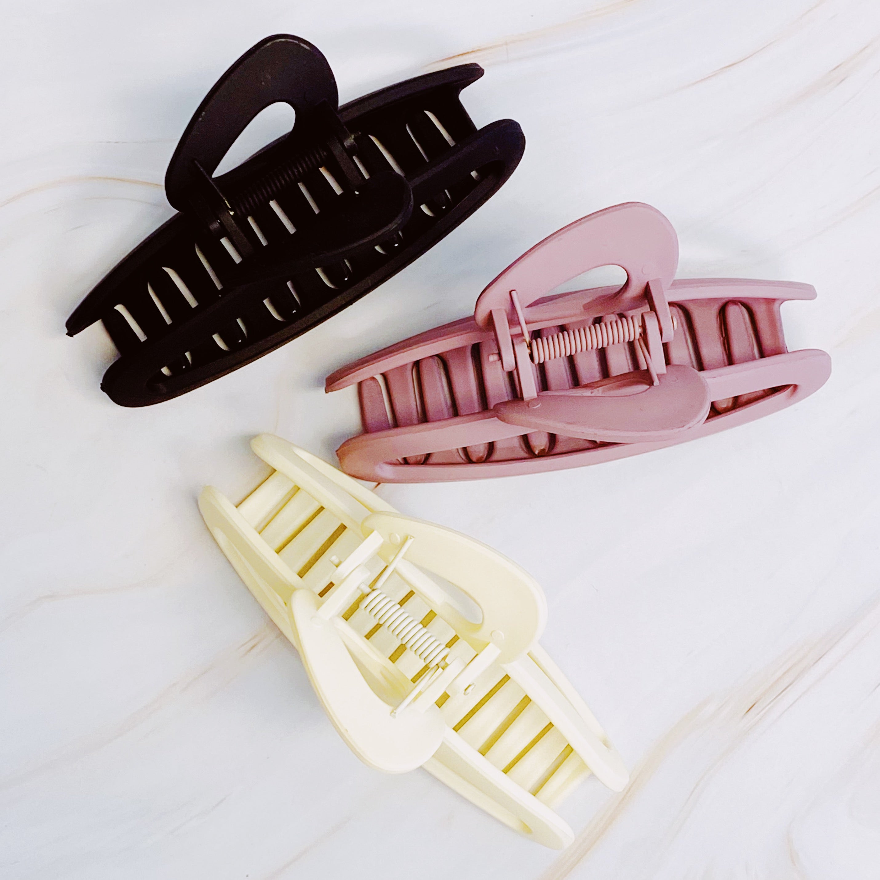 A stylish set of three hair claws in soft matte finish, showcasing various colors suitable for any hairstyle.