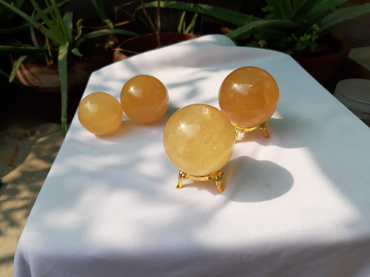 A beautifully hand-carved Honey Calcite Sphere with a warm yellow glow, showcasing its unique textures and natural markings.