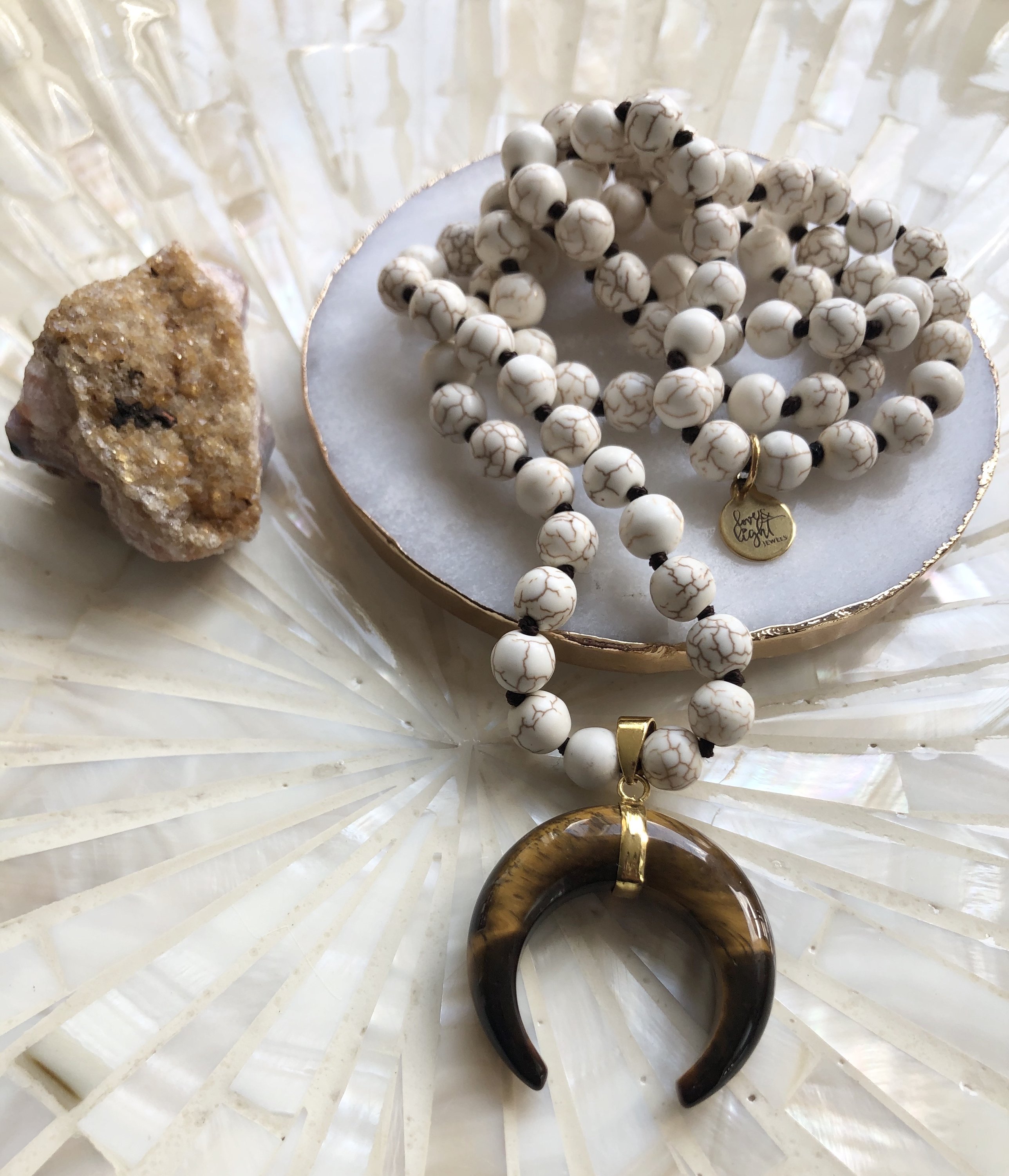 A beautiful Horn and Howlite Necklace featuring calming Howlite beads and a striking Tiger's Eye Horn pendant, elegantly displayed.