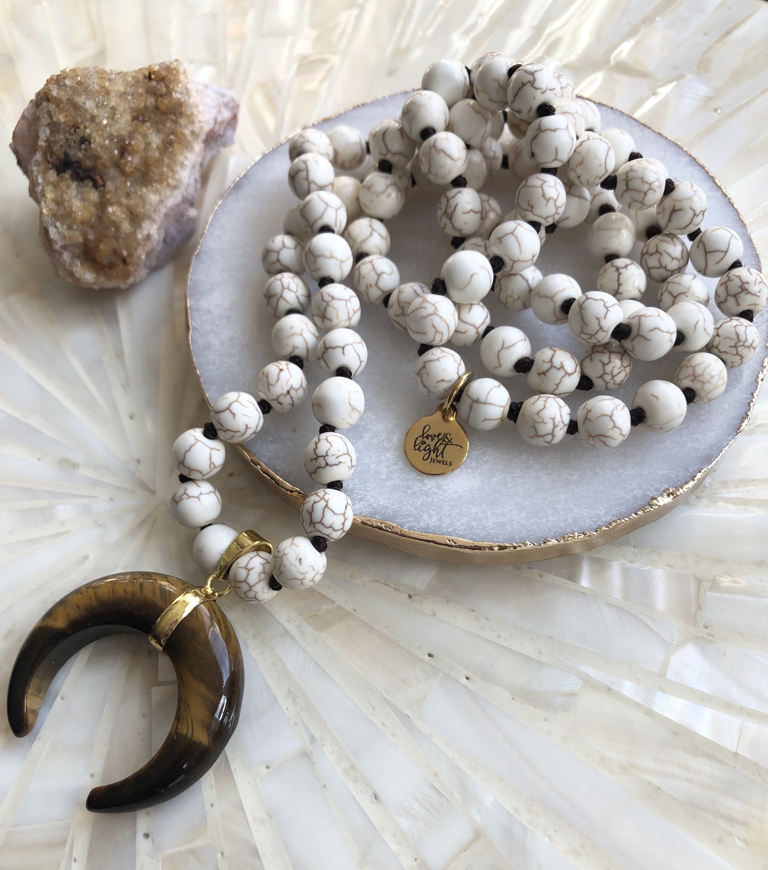 A beautiful Horn and Howlite Necklace featuring calming Howlite beads and a striking Tiger's Eye Horn pendant, elegantly displayed.