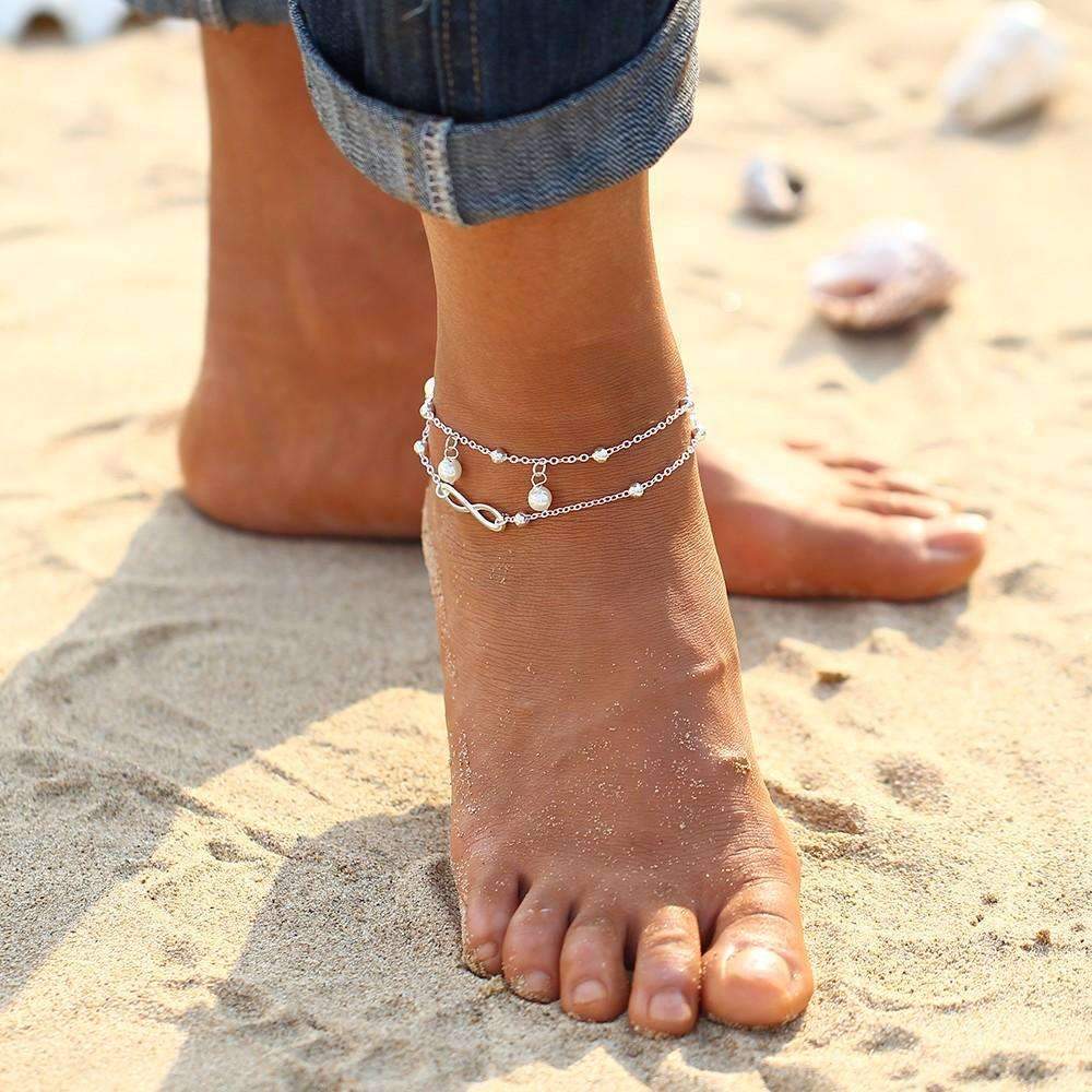 A stylish Infinity Pendent Pearl Anklet featuring a double layer design with simulated pearls and a zinc alloy finish.