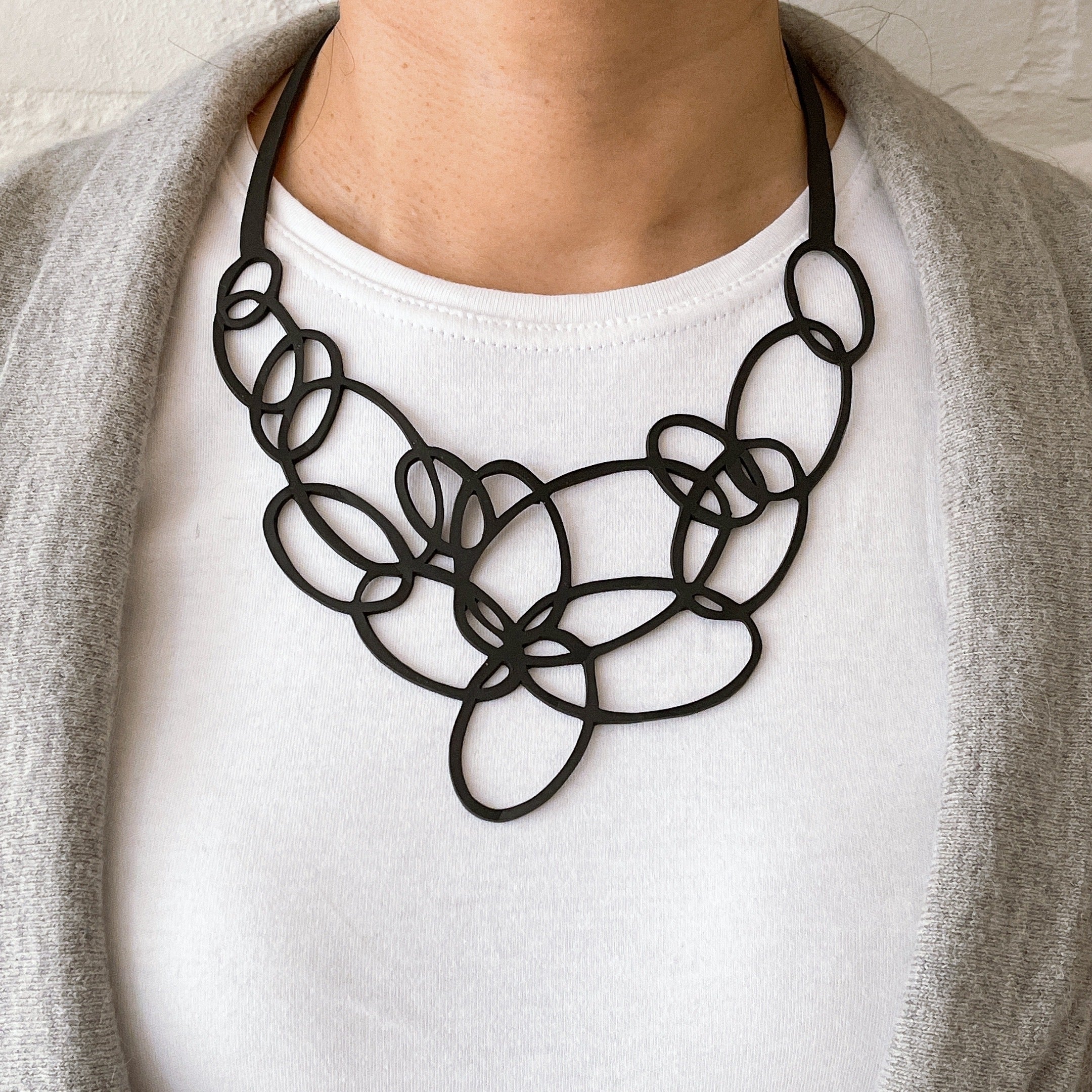 Elegant Infinity Upcycled Inner Tube Necklace made from reclaimed rubber, showcasing unique patterns and textures.