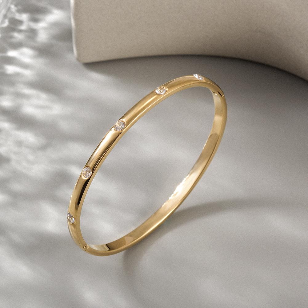 A delicate INITIAL Bangle featuring five sparkling stones, showcasing its smooth texture and elegant design.