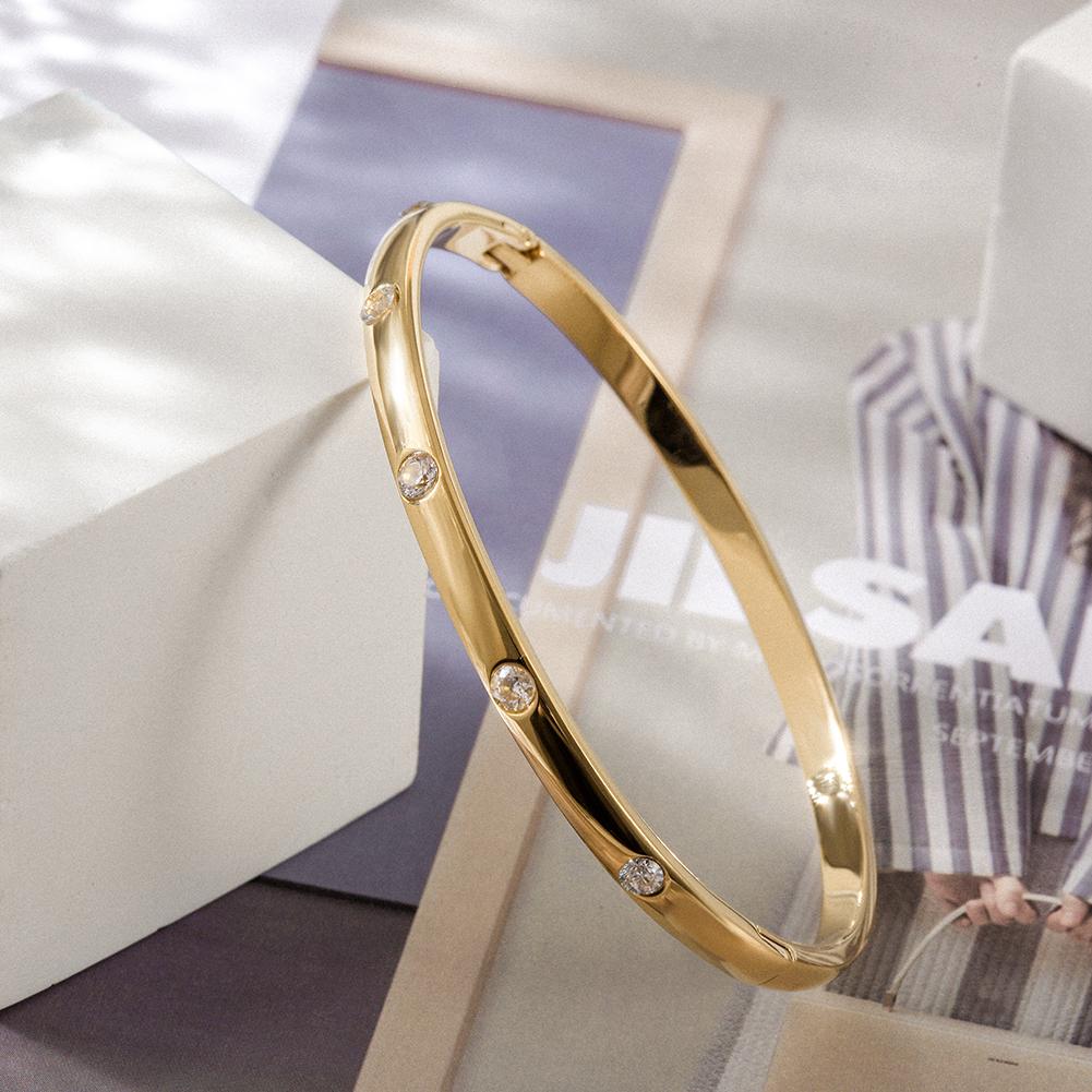 A delicate INITIAL Bangle featuring five sparkling stones, showcasing its smooth texture and elegant design.