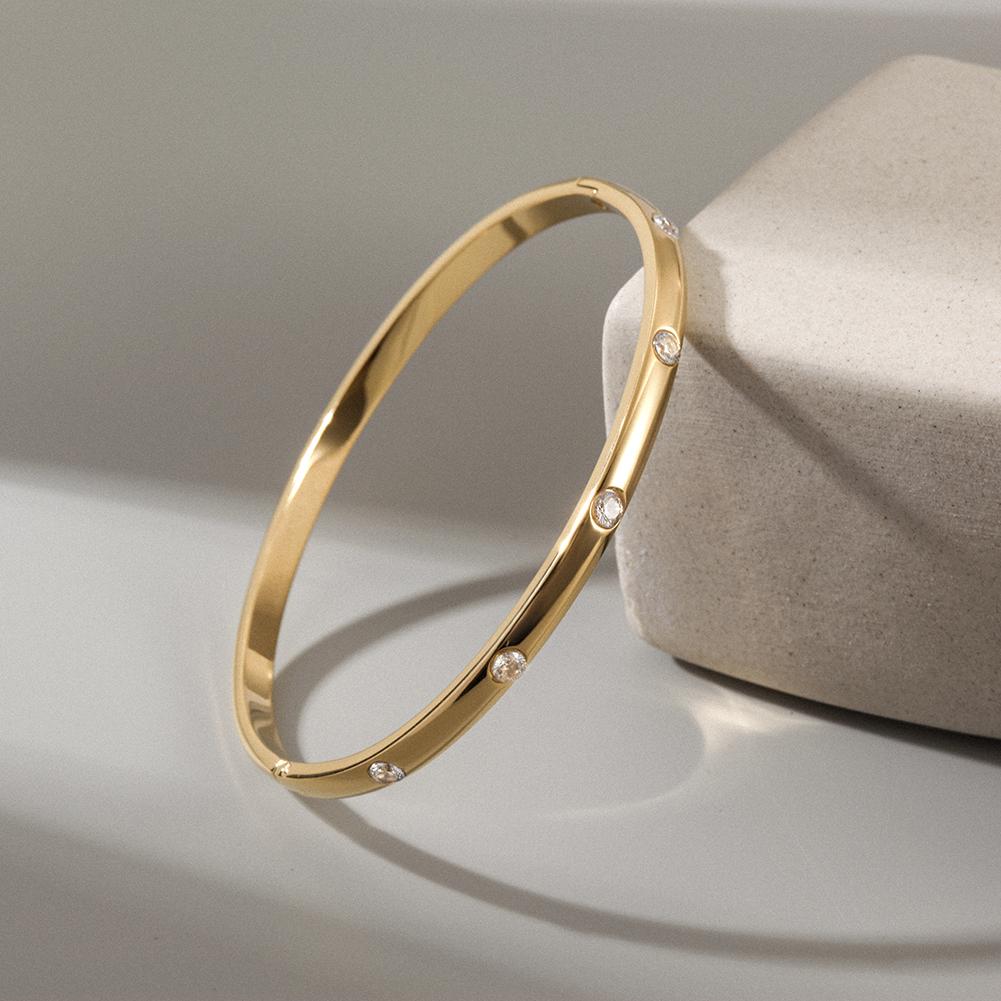 A delicate INITIAL Bangle featuring five sparkling stones, showcasing its smooth texture and elegant design.