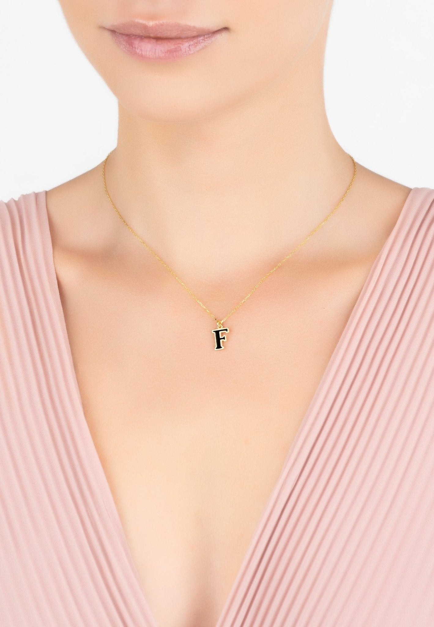 A delicate gold initial enamel necklace featuring a black enamel inlay, elegantly displayed in a signature jewellery box.