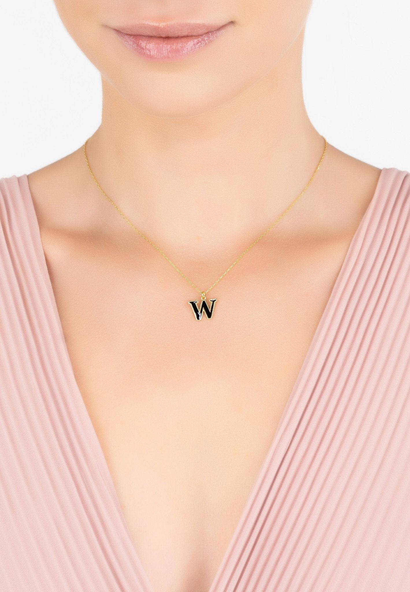 A delicate gold initial enamel necklace featuring a black enamel inlay, elegantly displayed in a signature jewellery box.