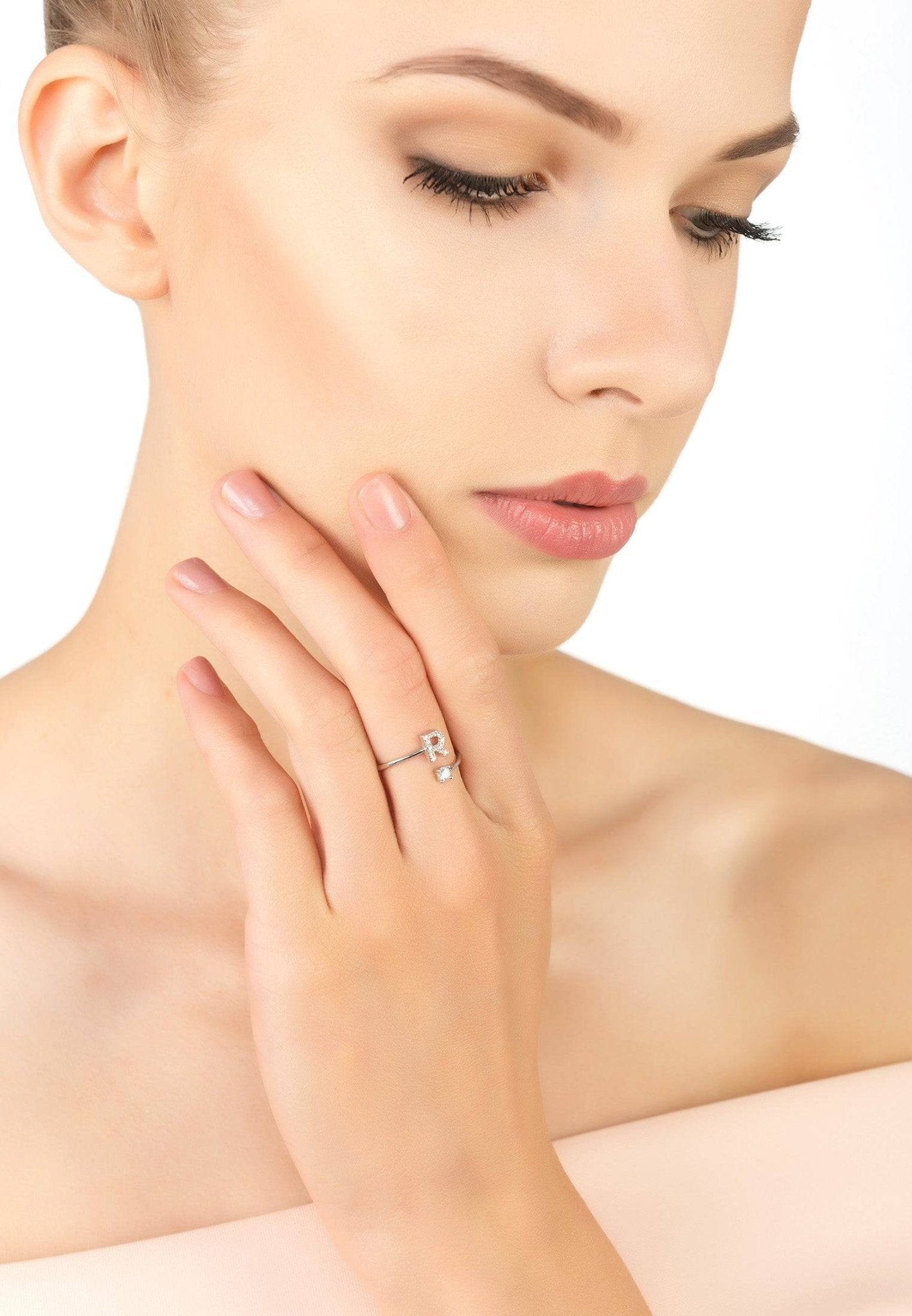 A delicate Initial Ring Silver R featuring an open band design with cubic zirconia accents, elegantly displayed in a jewellery box.