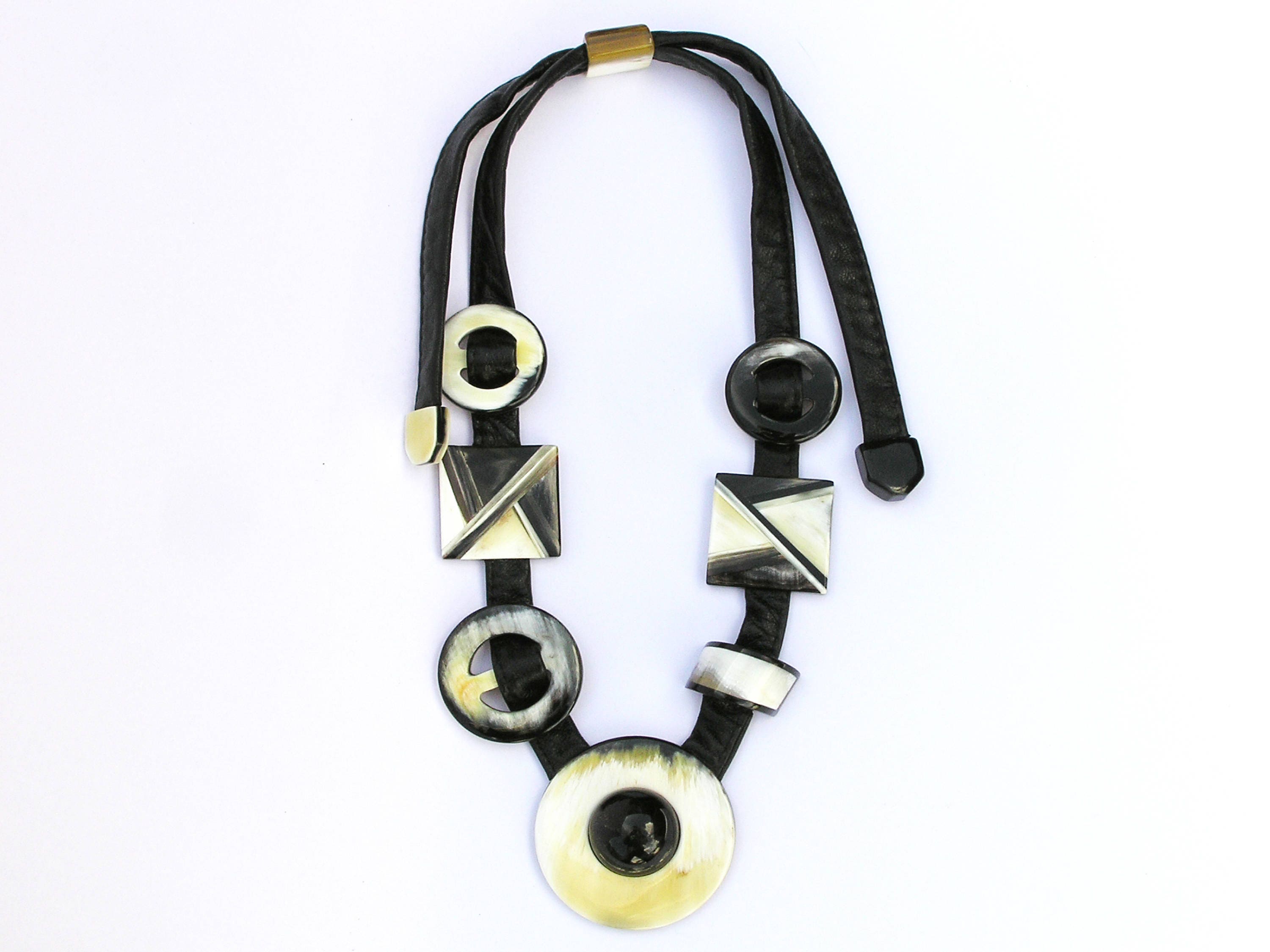 A beautifully crafted inlaid necklace made from natural buffalo horn, featuring a unique black and white design with a leather cord.