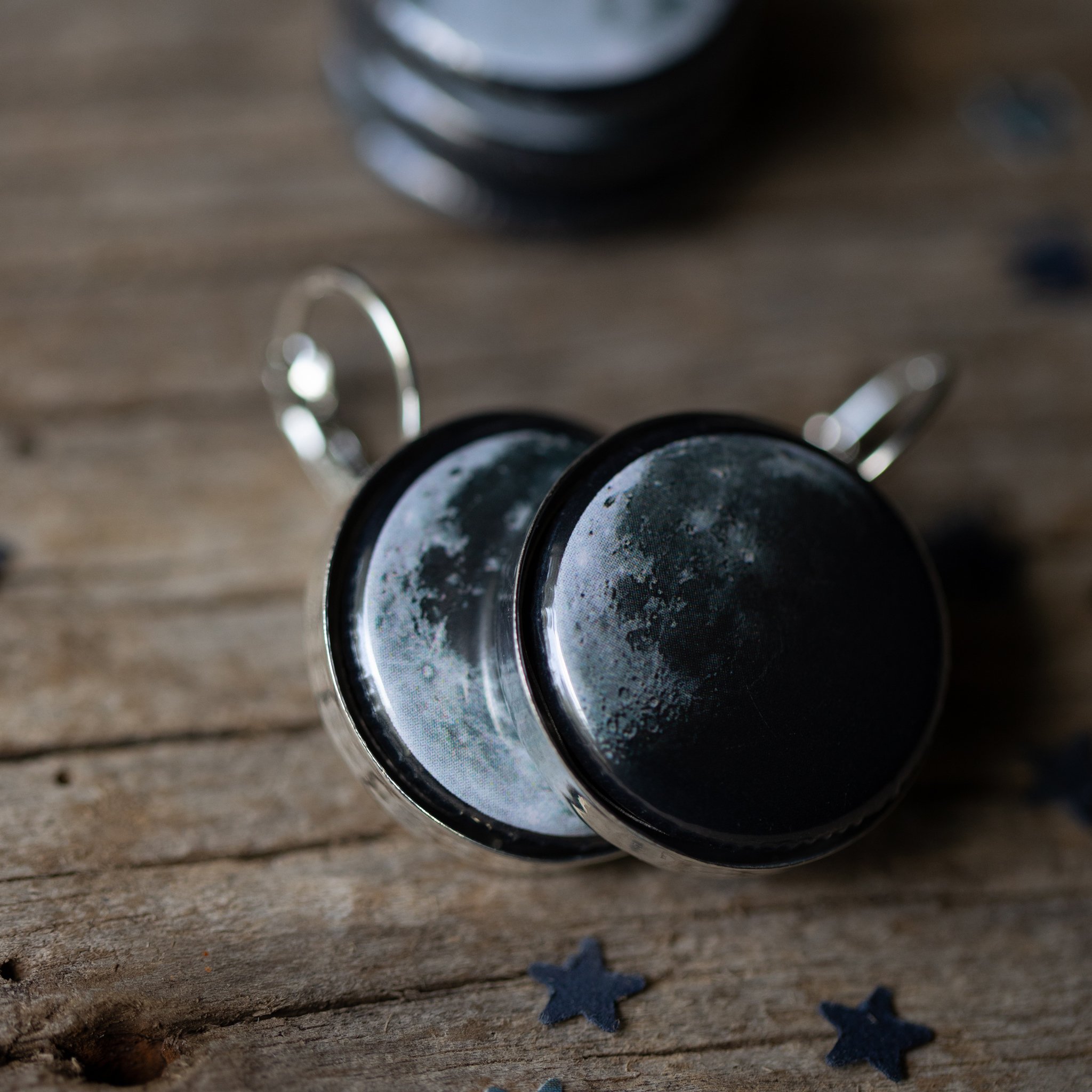 A pair of interchangeable earrings featuring five moon phases, available in silver and bronze tones, showcasing their unique magnetic design.