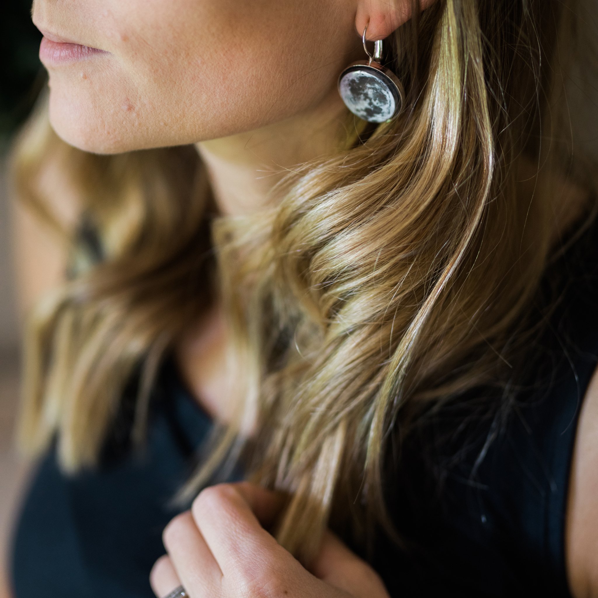 A pair of interchangeable earrings featuring five moon phases, available in silver and bronze tones, showcasing their unique magnetic design.