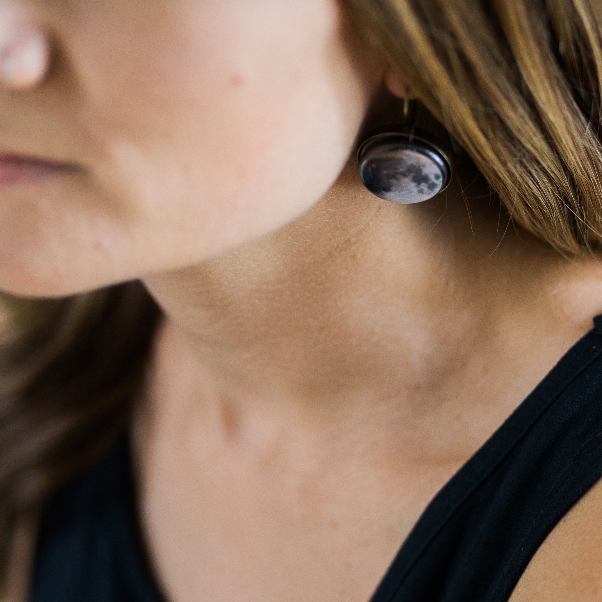 A pair of interchangeable earrings featuring five moon phases, available in silver and bronze tones, showcasing their unique magnetic design.